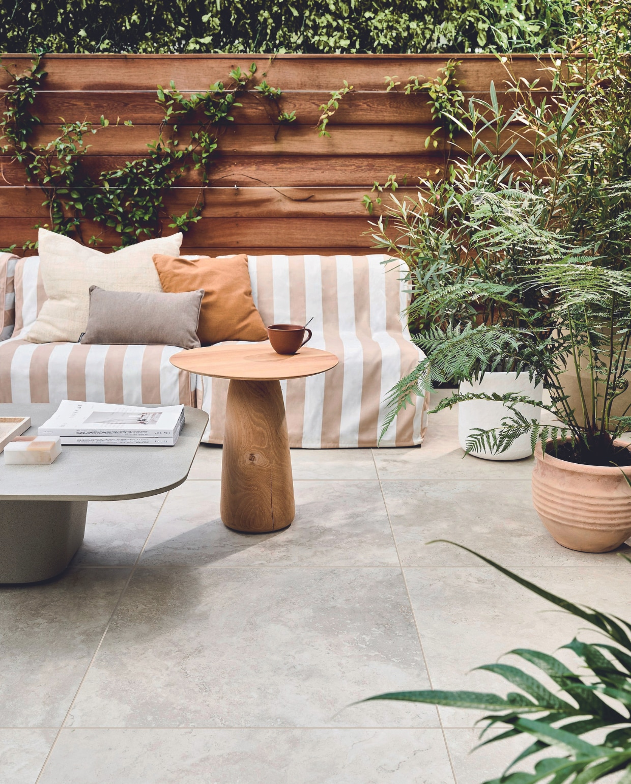 Tuintegel Solostone Uni Dust Off  White, 70x70 cm, per m² € 74,50. M.m.v. basiclabel.nl (opblaasbare fauteuils Sit on Air van vtwonen), dacks.nl (salontafel, bijzettafel), intratuin.nl (terracotta bloempotten, groot bruin kussen, klein bruin kussen), vtwonen.nl/shop (witte bloempot van Serax), zarahome.com (travertin plateau). Overig privébezit. vtwonen 05-2024 | styling Marlies Does | fotografie Sjoerd Eickmans