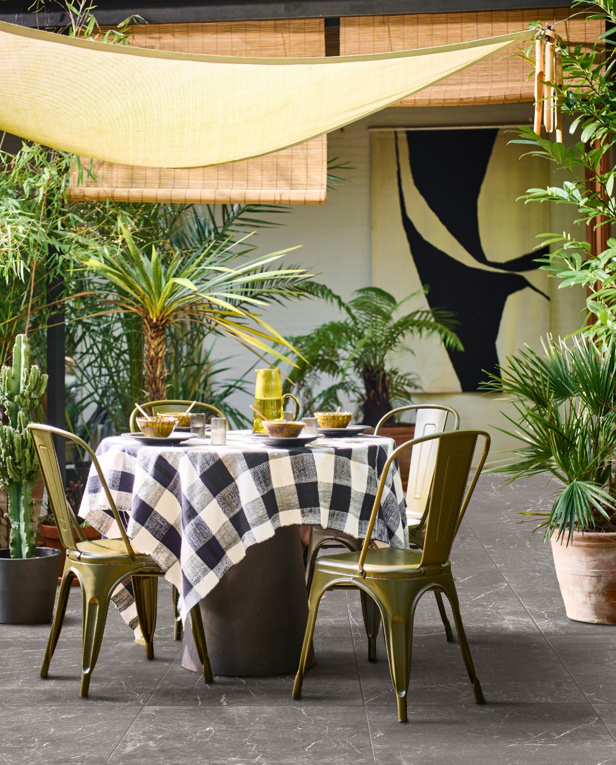 vtwonen collectie (metalen eetkamerstoel Afternoon in camouflage groen, 53x44x85 cm (bxdxh) € 99,95, tuintegel Solostone Outside Marble Antracite, 90x90 cm per m² € 89,50). M.m.v. basiclabel.nl (ronde betonlook eettafel Damon), householdhardware.nl (borden, Tamegroute kommen, houten lepels, glazen kan, tafelkleed), vtwonen.nl (waterglazen van Ferm Living, grijze bloempot). Overig privébezit. vtwonen 04-2023 | productie Tanja Saarberg | styling Marlies Does | fotografie Sjoerd Eickmans