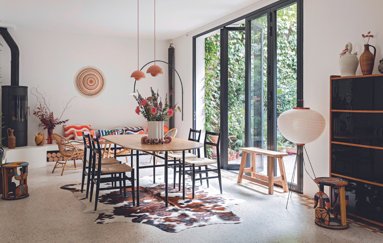 Eettafel Snaregade van Norm Architects, stoelen Superleggera van Gio Ponti voor Cassina, hanglamp Flowerpot VP1 van Verner Panton voor &Tradition, vloerlamp Akari van Isamu Noguchi, wandlamp No. 2 van Muller Van Severen voor Valerie Objects, krukken uit Mauritanië, vloerkleed tweedehands, rotan meubels vintage, wandobject Hélène Lefeuvre.