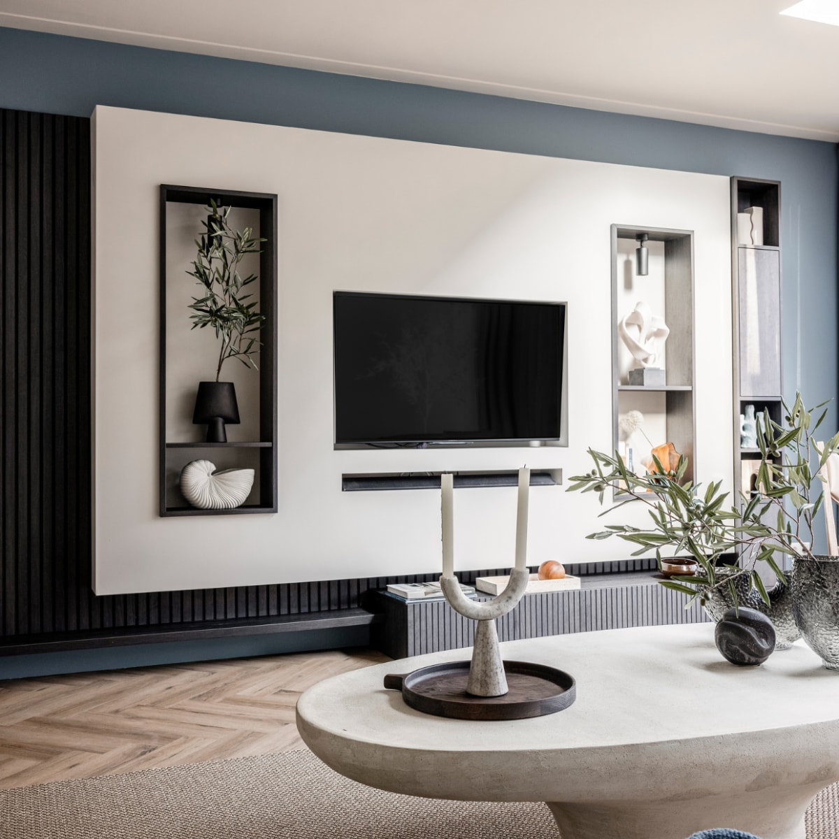 Verf muren bij de tv Denim Drift Flexa, Wandkast van de bewoners, geverfd in Sandy Beach Flexa, Wandmeubel met verticale lattenwand en ledverlichting Meijer Maat Interieurs, Bank Shark in de stof Sabbia 11 cream Eijerkamp, Vloerkleed Luca 6704 Cunera, Salontafel La Nena, Blauw plaid van Malagoon vtwonen, Marmeren siervorm met zware voet Nordal, Rond ornament Eijerkamp, Vazen Eijerkamp, Dienblad Eijerkamp, Kandelaar met twee armen Nordal, Kaarsen Hema, Olijftak 138217 Silk-ka. Overig privébezit Weer verliefd op je huis seizoen 17 aflevering 4 | styling Liza Wassenaar | fotografie Sonja Velda