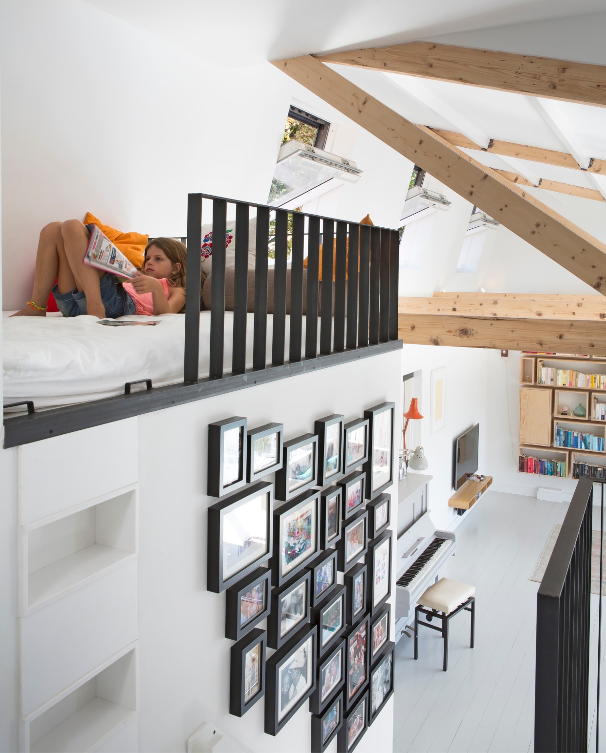 Houtwerk maakte ook een vide naast de trap naar boven. Daar kunnen de kinderen lekker lezen. De wand doet dienst als fotogalerij met snapshots van vrienden en familie. vtwonen 07-2017 | fotografie Henny van Belkom