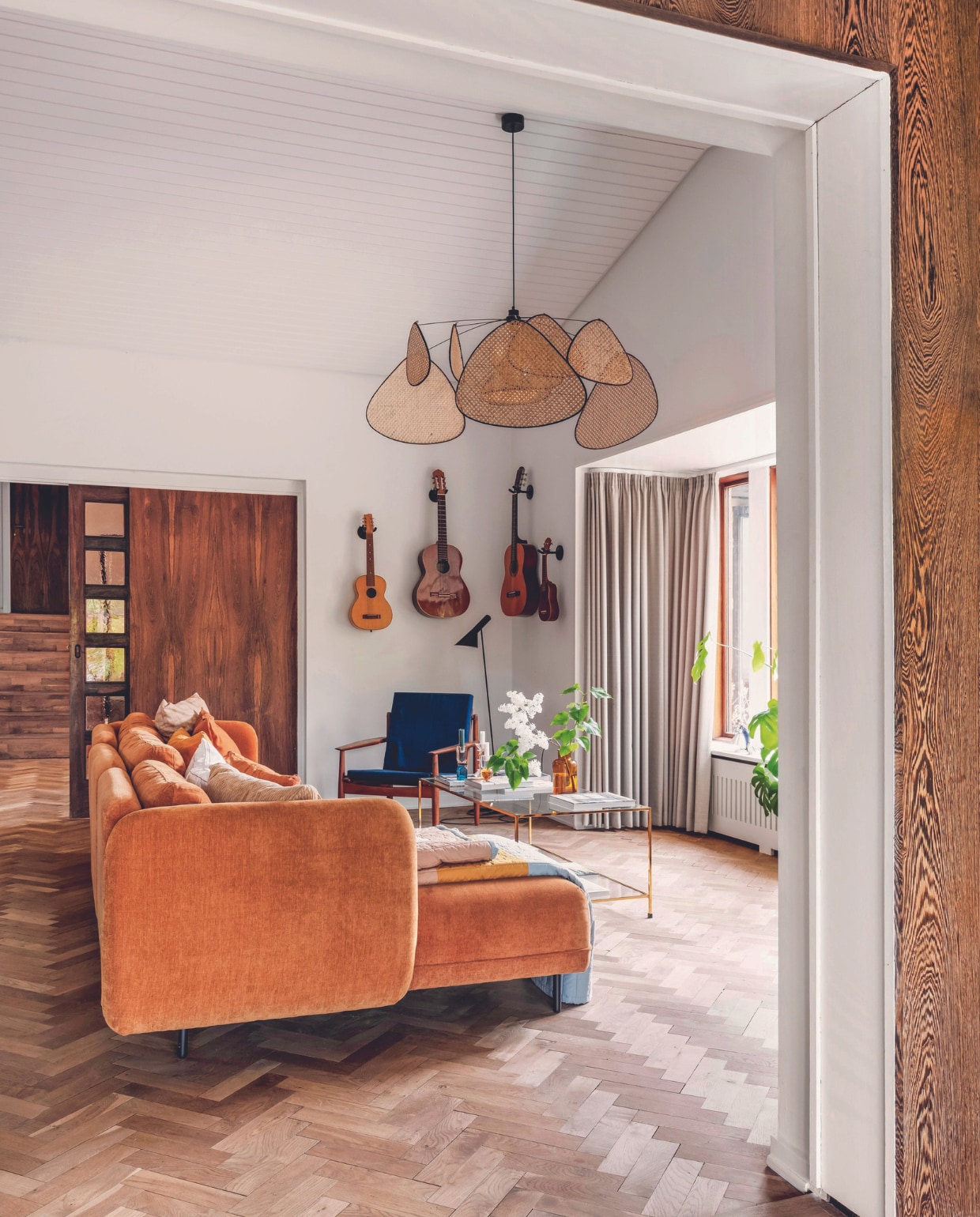 Stenen terras aangelegd door de vorige bewoners, tuintafel Fermob, stoelen Fdb Møbler, schapenvachten Ikea, tafelkleed Fabelab. De parketvloer is 75 jaar oud, bank Sofacompany, lamp Market Set, oude gitaren van Michaela, salontafel Ellos, kandelaars C’est Bon, vaas H&amp;M Home. vtwonen 06-2024 | fotografie Christina Kayser Onsgaard | styling Rikke Graff Juel