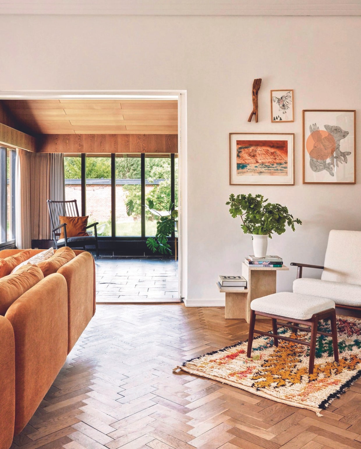 Witte fauteuil met voetenbankje gekregen en opnieuw gestoffeerd. Vloerkleed Craft Sisters, litho Marius Olsen, houten beeld gemaakt door een familielid, afbeeldingen met vos en uil Kristine Mandsberg. vtwonen 06-2024 | fotografie Christina Kayser Onsgaard | styling Rikke Graff Juel