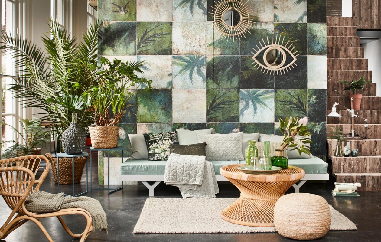 Vliesbehang Exotic Damier per m2 € 95,- (Wall &amp; Deco). Daybed op maat gemaakt vanaf € 350,- (Combitex). Rieten Fox Chair naturel, 80x64x80 cm € 699,-, grijze kussens Deco Plain cotton van Tine K, 50x75 cm per stuk € 69,-, vloerkleed Jute Twist, 140x200 cm € 200,-, Palma table rotan € 296,- (l’Etoile Conceptstore). Wafelplaid Coriander € 69,95 (www.stapelgoed.com). Sidetableset Mimi Petrol € xxxx, kussen Vintage velvet grijs € 39,95, kussen Silver velvet, 50x50 cm € 39,95, kussen wafel € 39,95, groen kussen met pailletten, 30x50 cm € 37,95, quilted plaid Shadow € 99,95, flesvaas met gehaakte buitenkant € xxxx, (Coming Lifestyle). Kussen bloemprint UNC Amazon Flower groen € 23,95 (Livv Lifestyle). Op de salontafel: groene schaal € 35,- (De Weldaad), groene glazen vaas met gouden hals € 39,50, drinkglazen met deksel en rietje € 2,50 (Nordal), groene aardewerken vaas € 45,- (Six and Sons). Industriële lamp op de trap € 99,95 (Stapelgoed). Gevlochten poef € 68,50, gevlochten mand op bijzettafel set van 3 € 77,50 (Madam Stoltz). Grote gevlochten mand met palm € 59,50 (Nordal). Spiegel met ronde rotanrand € 159,50, groene glazen karaf € 25,50 (Household Hardware). Spiegel in de vorm van een oog € 79,95 (Couleur Locale). Groene glazen vaas op trap € 12,95 (H&amp;M Home). Overig privébezit. vtwonen 07-2016 | Styling Cleo Scheulderman | Fotografie Jeroen van der Spek