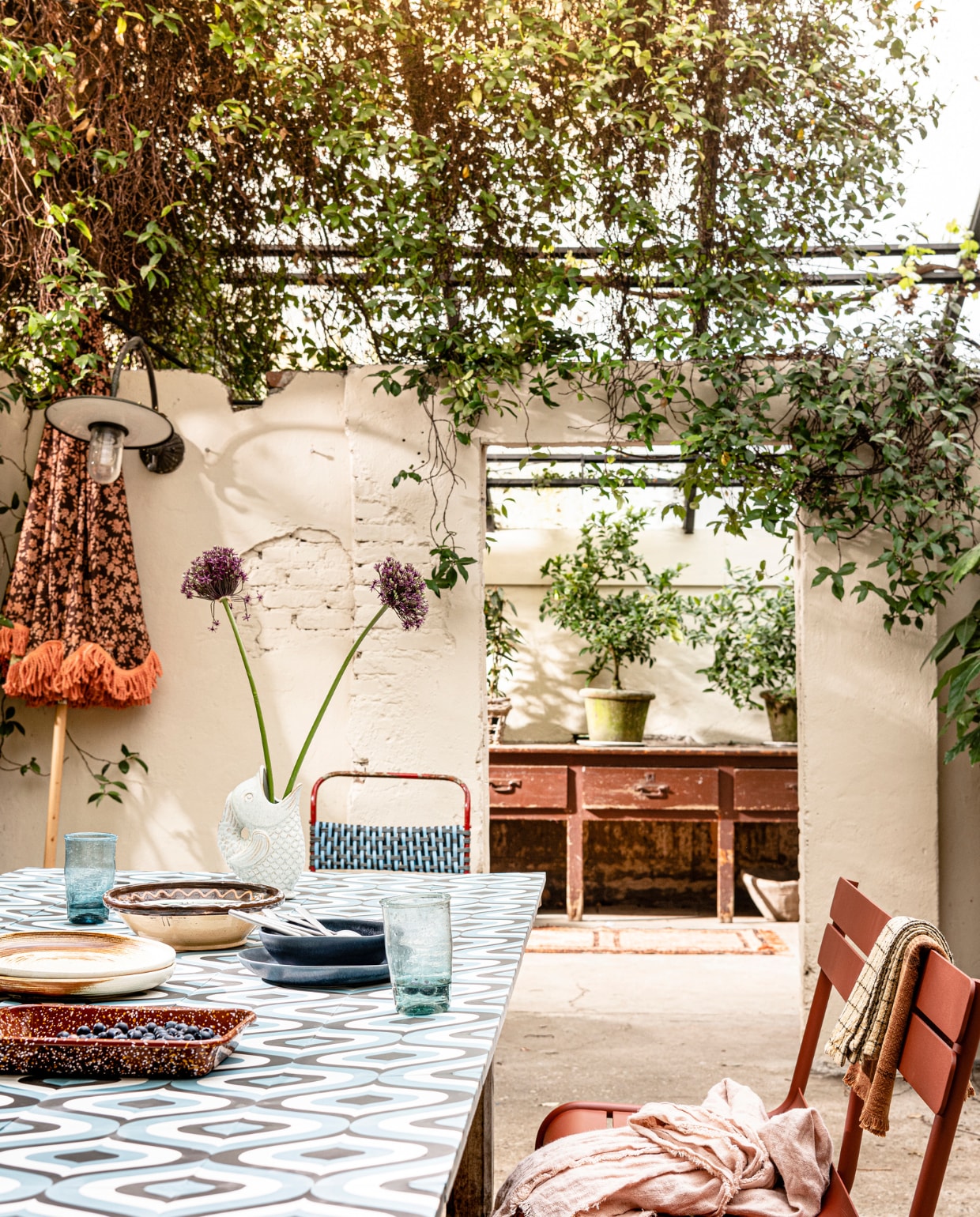 Oude tafel met daarop cementtegels Oceana, 20x20 cm (lxb) per m² € 89,-
(tegelbv.nl). Oude stoel met kunststof geweven zitting € 95,-, wandtafel vanaf € 500,-, oude schaal € 25,- (vandijkenko.nl). Parasol van HKliving € 295,- (vtwonen.nl). Vloerkleed Madam Stoltz € 60,- (deens.nl). Bankje van Fermob, 118x85,5x56 cm (bxhxd) € 515,- (dacks.nl). Roze linnen tafel- kleed € 39,95 (urbannatureculture.com). Theedoeken van Madam Stoltz € 10,-
(deens.nl). Emaillen bak van Hay € 25,-, borden van HKliving € 17,95 (vtwonen.nl). Glazen € 8,75 en donkerblauwe borden vanaf € 22,- (bungalow.dk). Bestekset, set van 3 € 23,95 (hkliving.nl). Vissenvaas van Madam Stoltz € 20,- (deens.nl). Planten en potten privébezit. vtwonen 07-2021 | styling Marianne Luning | fotografie Sjoerd Eickmans