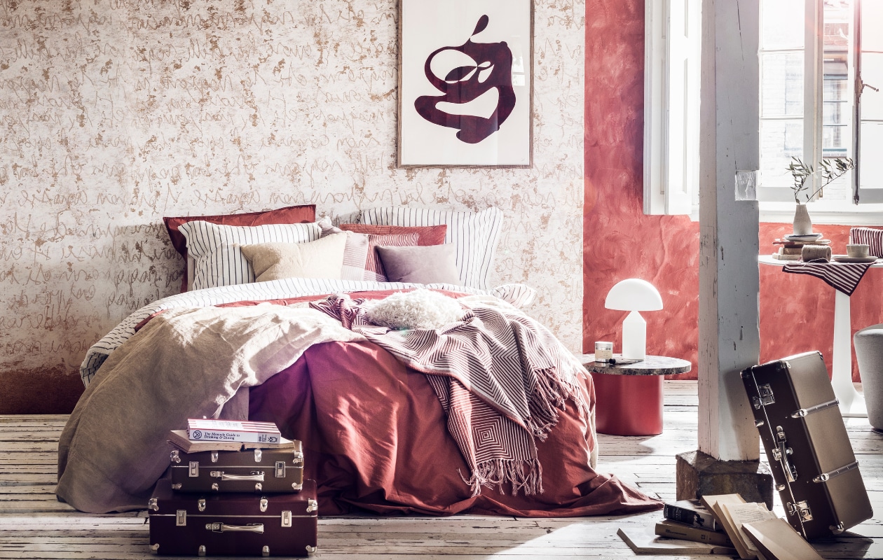 Muurverf kleur Drummond 16 van Little Greene, per liter € 43,50 (De Ru). Behang met letters, prijs op aanvraag (Wall&amp;decò). Beddengoed wit met grijze streep € 49,99, rood beddengoed € 49,99, sprei wit met rode streep 130×170 cm € 39,99, geblokte kussenhoes, 50×50 cm € 7,99, grijs-witte linnen japon € 39,99 (H&amp;M Home). Zandkleurige sprei, 130×170 cm € 89,99, kussen, 50×50 cm € 22,99 (Zara Home). Grijs kussen, 40×40 cm € 69,- (Bolia). Ronde bijzettafel Enoki gebruikt als nachtkastje € 860,-, witte lamp € 597,-(Mobilia). Toilettas rood met witte strepen € 24,95, rood-wit handdoekje op tafel € 5,95 (Anna + Nina). Witte tafel met afgeronde randen € 1386,-, grijze stoel € 1098,- (Edha interieur). Schotels per stuk € 29,-, kom € 25,-, vaasje € 35,- (Annemieke Boots Ceramics). Koffers vanaf € 45,- (Archive Store). Boek The Monocle Guide to Drinking &amp; Dining € 29,95 (Six and Sons). Kunst aan de muur € 620,- (Cate Adriana). Overig privébezit. vtwonen 07-2018 | styling Liza Wassenaar | fotografie Sjoerd Eickmans