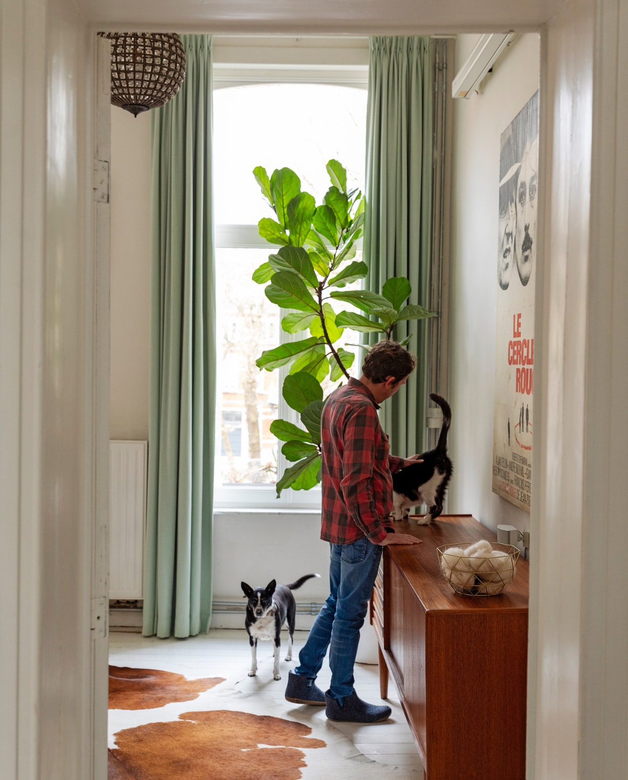Hanglamp markt Marollen, gordijnen Hema, plant Aldi. Poster oude filmposter uit Frankrijk op doek laten spannen. Vloerkleed koevel van de markt, dressoir Møbelfabrik. Overig onbekend. vtwonen 10-2023 | styling Ilona Jongepier | fotografie Dana van Leeuwen
