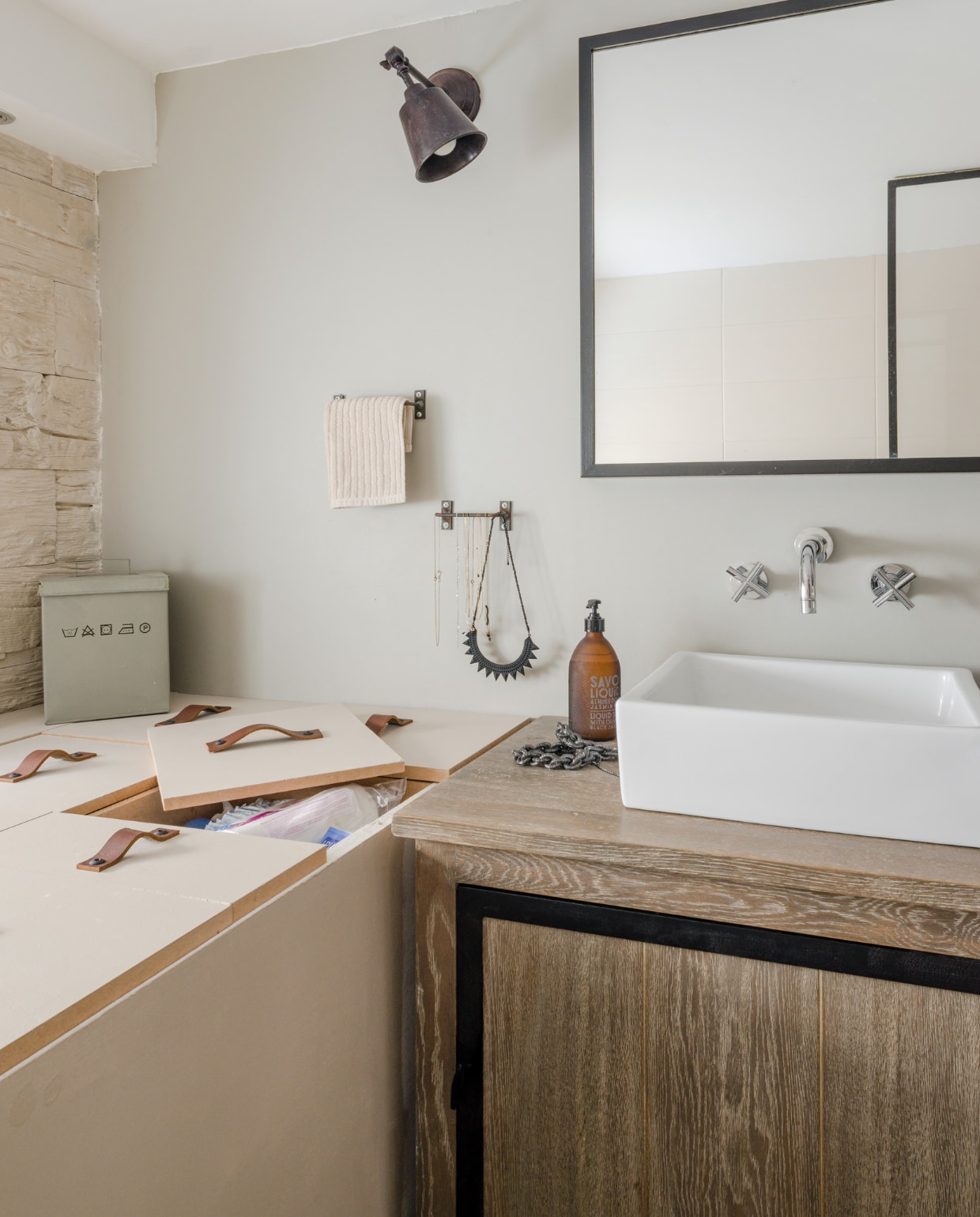 Tegenover de Italiaanse douche werden een kleine zitplek getimmerd, en een blok met opbergunits, met stroken leer als handgreep. De wandlampen zijn van Castorama, de metalen boxen van Bloomingville. vtwonen 03-2015 | Fotografie Julien Fernandez / amandinejules.com