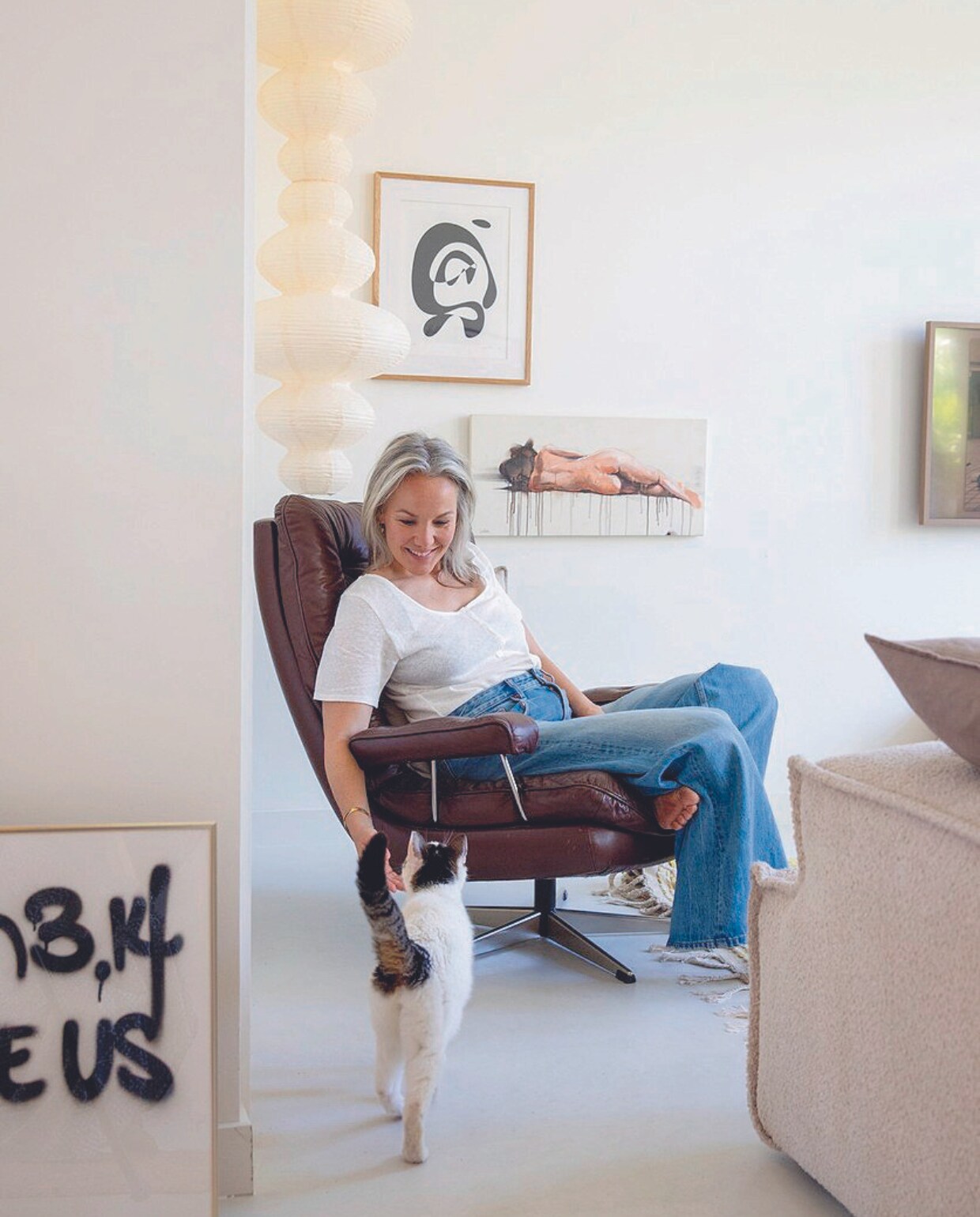 Kunstwerk op de grond Laser 3.14, vintage stoel Marktplaats, bank Zitmaxx Wonen, bruin kussen H&amp;M Home, witte lamp zelf samengesteld, zwart-wit schilderij Cate Adriana, schilderij van vrouw Dario Moschetti, televisie Samsung. vtwonen 07-2024 | styling Ilona Jongepier | fotografie Dana van Leeuwen