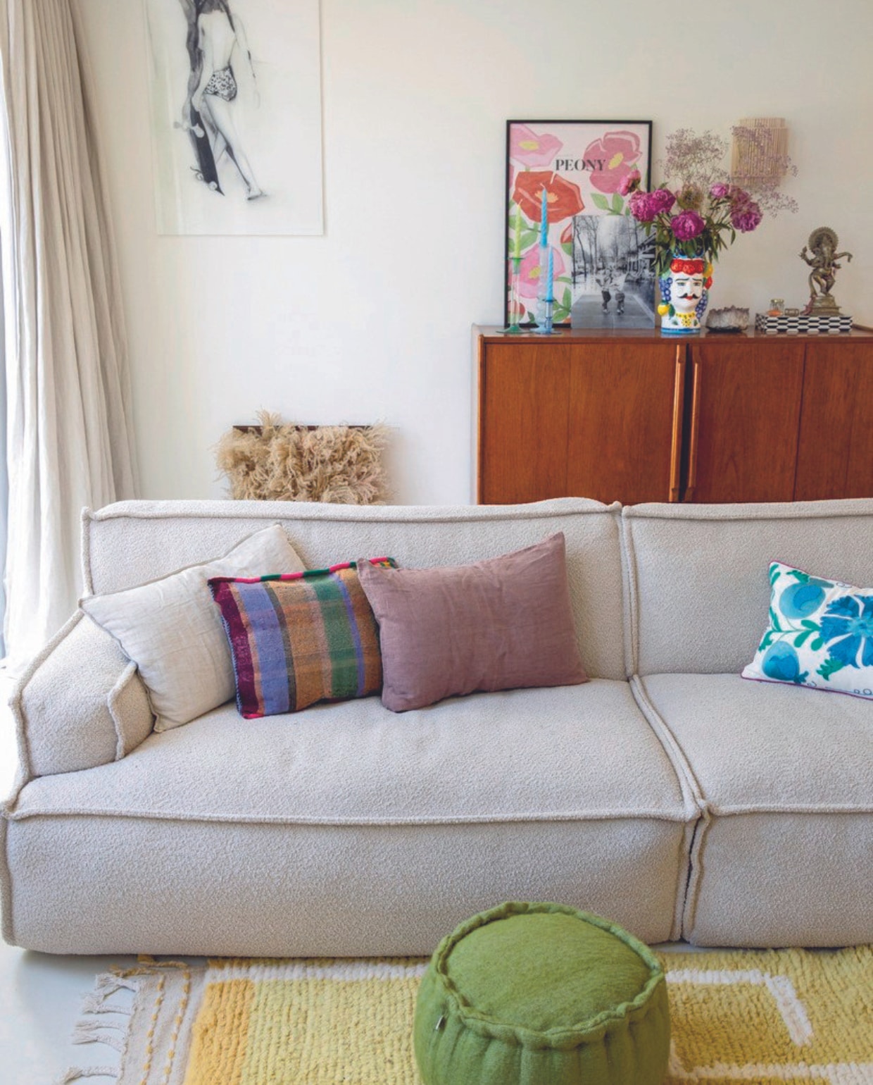 Bank Zitmaxx Wonen. Vloerkleed, poef, geblokt kussen, dressoir, kunstwerk op de grond en zwart-wit doosje Maison Aimélie. Blauw gebloemd kussen, gekleurd schilderij met bloemen en vaas Anna + Nina. Overige kussens H&amp;M Home. vtwonen 07-2024 | styling Ilona Jongepier | fotografie Dana van Leeuwen