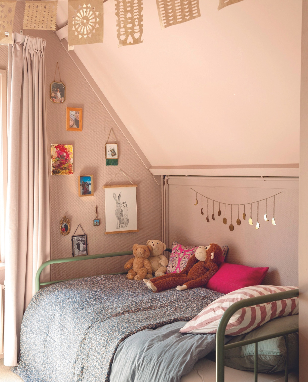 Bed Slaapidee. Beddengoed, sprei, groen kussen H&M Home. Gestreept kussen Wehkamp. Roze kussen en gebloemd kussen Anna + Nina. Slinger Urban Outfitters, muurkleur Light Peachblossom van Little Greene. Schilderijen en foto’s zelfgemaakt. Gordijnen Hema. vtwonen 07-2024 | styling Ilona Jongepier | fotografie Dana van Leeuwen
