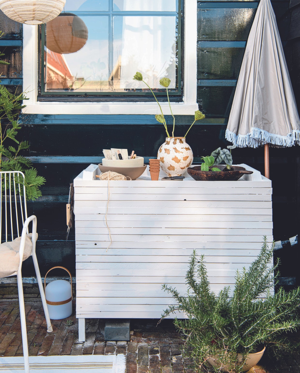 Mimosaboom € 59,95, rozemarijnplant € 24,95 (bloementuinaandezaan.nl). Metalen stoel Arty € 135,- (tikamoon.nl). Parasol Pescara van Human Nature, polyester en staal, 180 cm (Ø) € 44,99 (anwb.nl). Linnen kussenhoes € 14,99 (hm.com). Touw op houten klos € 4,80 (hobby-koopjes.nl). Keramieken vaas Heron € 62,95 en mangohouten schaal Modern rustic van Urban Nature Culture € 79,95 (zaanschfaamwebshop.nl). Terracotta schalen kringloop, geverfd met verfresten.Tafellamp € 49,99 (zarahome.com). Katoenen vloerkleed Sortsö, 55x85 cm € 3,99 (ikea.nl). Kweekpotjes, biologisch afbreekbaar, set van 5 € 1,95, schep € 2,95, vurenhouten steeketiketten, set van 10 € 2,50, tuinschaar € 4,95 (dille-kamille.nl). Smeedijzeren siernagel € 5,18 (deurbeslag.nl). Overig privébezit. vtwonen 07-2024 | styling Myla Griese | fotografie Louis Lemaire