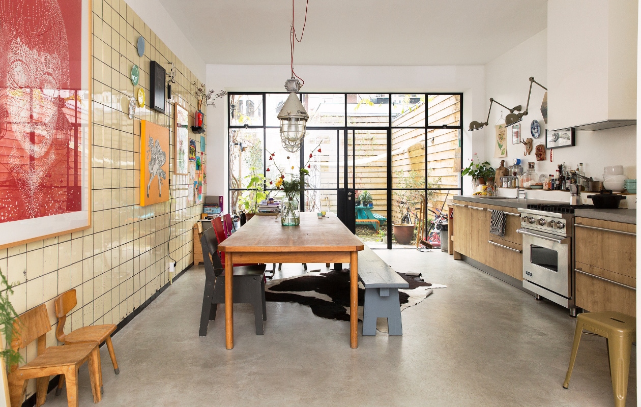 Eettafel gevonden in een oude loods, grijze bank zelf gemaakt. Stoelen van Piet Hein Eek, van Eames gevonden bij het grofvuil. Hanglamp van Neef Louis. Vazen van Een Bloemetje op Tafel. Bank en kleed Loods 5. Blauwe bank gemaakt door Frank de Bruijn van Supergoed. Groene lamp van Snowpuppe. Kastje en veel kaarten aan de muur van Spullen voor in je huis. Rood kunstwerk van Inez Odijk, schilderij met aap van Freya Wisman, werk in zwarte lijst van Piet Parra, bord met gezicht van Donna Wilson. Witte kruk achterin van Dulton Company, kruk op de voorgrond van Tolix, koeienhuid van Ikea. vtwonen special binnenkijken 121-2017 | styling Emmy van Dantzig | fotografie Jansje Klazinga