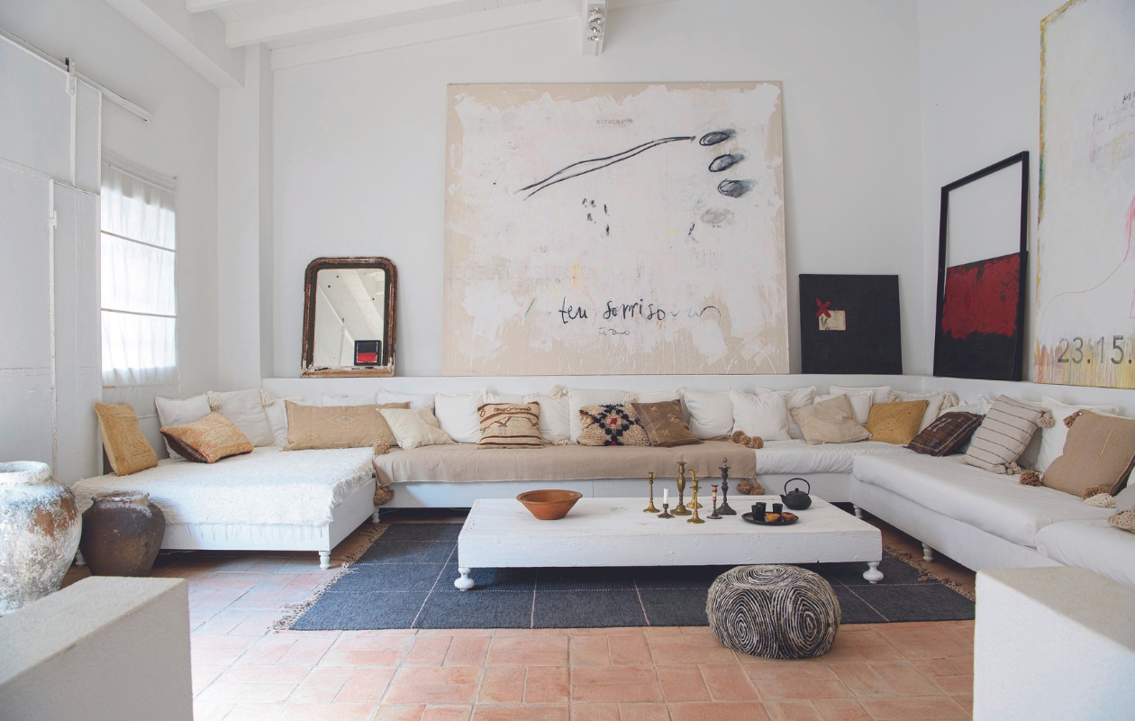 Bank maatwerk, Marokkaanse kussens Liv Conceptstore, kandelaars en spiegel vintage, terracotta schaal lokaal, kruiken links Gosto Interiores &amp; Arte. Schilderijen Eric de Bruijn. vtwonen 07-2024 | productie Inside Homepage | styling Anja Bas Backer | fotografie Louis Lemaire
