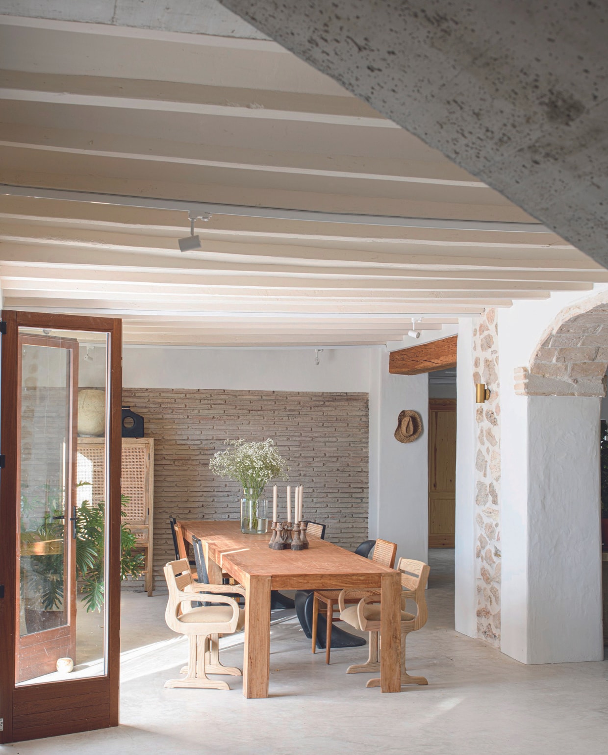 Betonvloer door een lokaal bedrijf, muurverf Ral 9010, plafondverf Nutria 15. Eettafel, eetkamerstoelen, vaas, kandelaars en kast ByDennis. vtwonen 07-2024 | productie Insidehomepage | fotografie Louis Lemaire