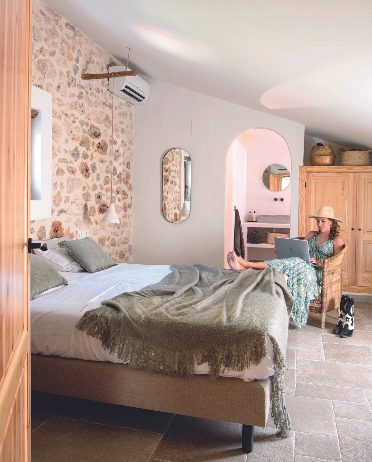 Tegelvloer BigMat. Bed, kussens, sprei, wandlamp, ovale spiegel, ronde spiegel, houten kast en manden op kast ByDennis. vtwonen 07-2024 | productie Insidehomepage | fotografie Louis Lemaire