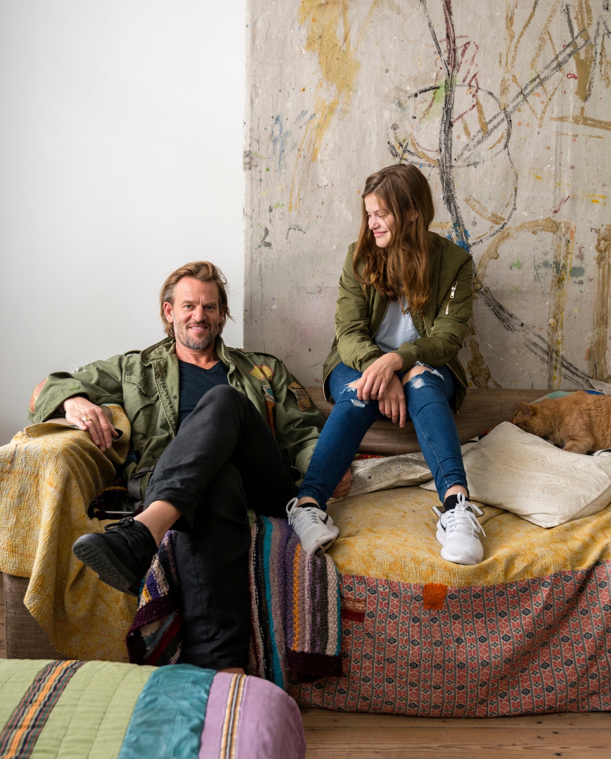 Jasper en dochter Lisa op de bank. Achter de bank hangt eigen werk. Op de bank liggen beschilderde quilts en kussens uit Bali. vtwonen 10-2016 | styling Emmy van Dantzig | fotografie Stan Koolen