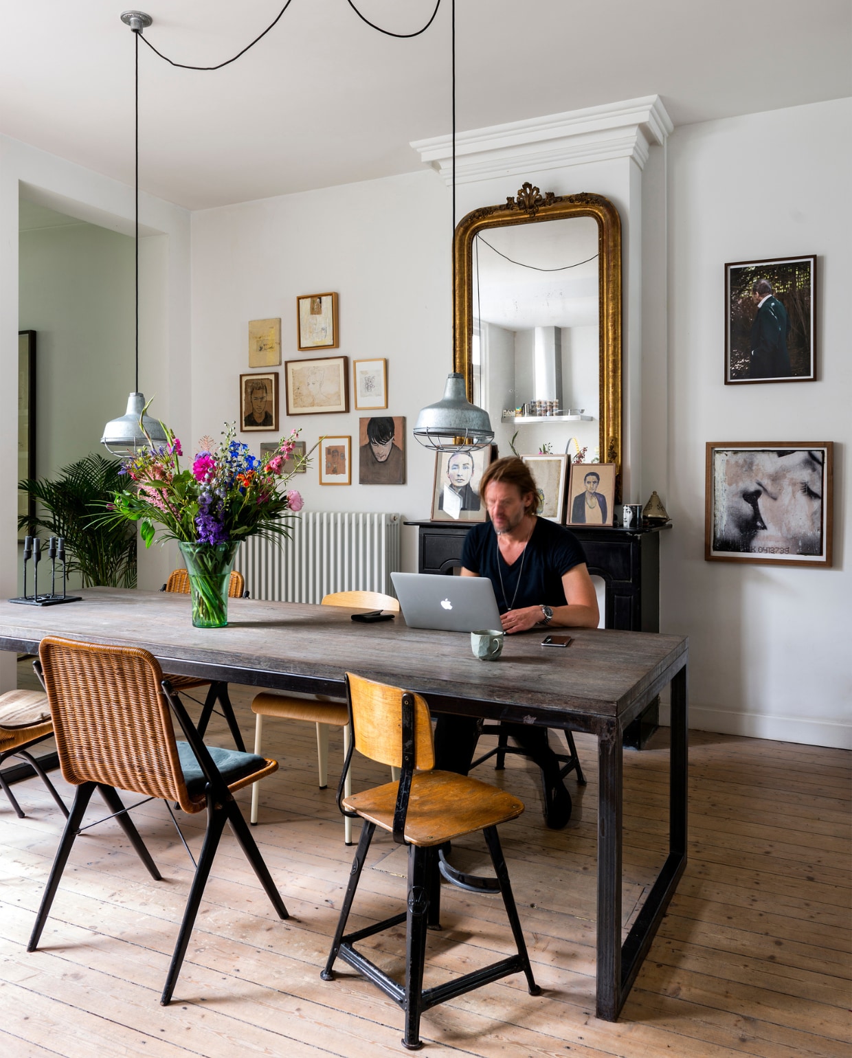 Jasper aan de tafel uit Bali. Rechts een stoel van Rowac, daarnaast een tweedehands rieten stoel. De stoel met witte poten is een Jean Prouvé. Naast de schouw hangt eigen werk op papier en doek. Spiegel gevonden bij Anouk Beerents. Jasper: ‘Ze verkoopt antieke spiegels in een van de mooiste ruimtes van Amsterdam.’ Foto van Lucian Freud door Koos Breukel, daaronder een beschilderde foto van Jasper. Lampen boven de tafel van een vintage markt. Kandelaar Heima op tafel van Normann Copenhagen. Mok van Urban Outfitters. vtwonen 10-2016 | styling Emmy van Dantzig | fotografie Stan Koolen