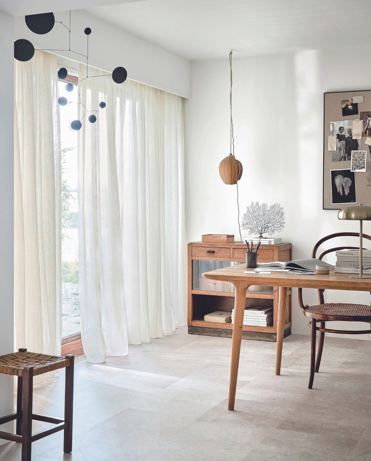 Inbetween transparant gordijn op maat in stof Wide Stripes, kleur Ecru White Stripe (2316), per meter vanaf € 27,99.M.m.v. kringloop (kruk, kast), zarahome.com (prikbord, tafellamp, pennenbak), demuseumwinkel.com (zeewaaier), moduleo.com (vloer), lpln.de (mobile). vtwonen 08-2024 | styling Kim van Rossenberg | fotografie Sjoerd Eickmans