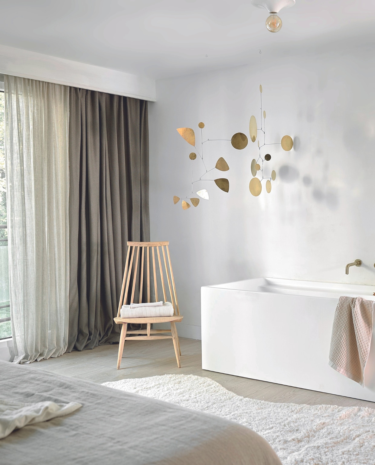 Inbetween transparant gordijn op maat in stof Peep Through, kleur Flax (2315), per meter vanaf € 36,99 en verduisterend gordijn op maat in stof Soft Bouclé, kleur Taupe (2306), per meter vanaf € 32,99.M.m.v. zarahome.com (beddengoed, handdoek), noyastudio.dk (vloerkleed), lpln.de (mobile). Overig privébezit. vtwonen 08-2024 | styling Kim van Rossenberg | fotografie Sjoerd Eickmans