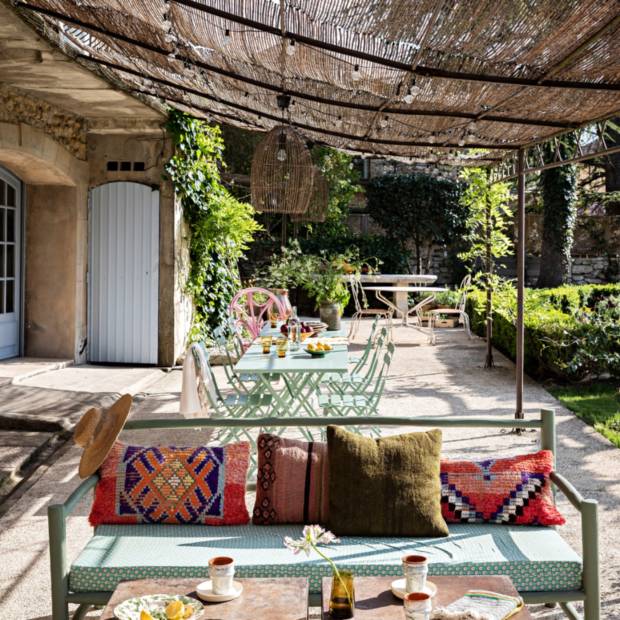 Franse tuin met een groene bistroset en kleurrijke kussens op de buitenmeubels