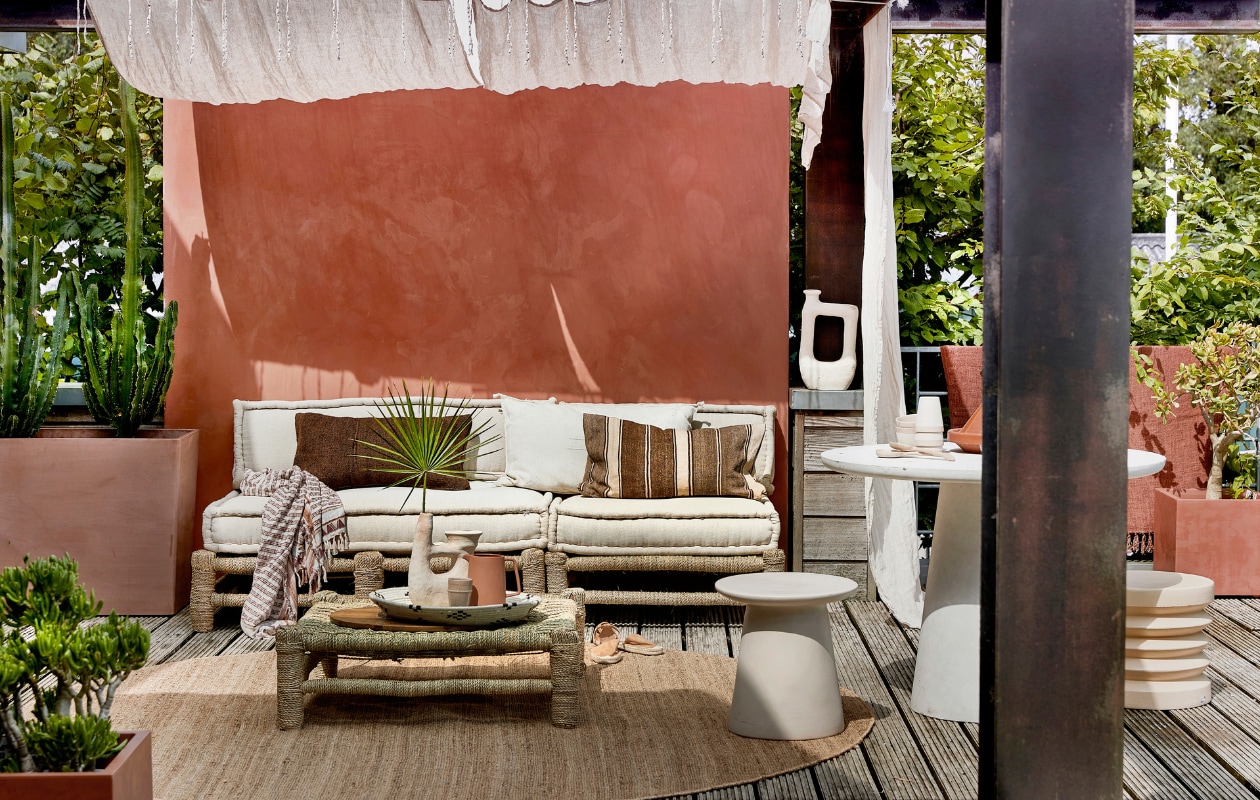 Met touw omwikkelde houten loungebank Hassan, 80x80 cm € 255,-, 120x80 cm € 335,-, zitkussens vanaf € 109,-, zandkleurige vaas Tamegroute met 2 armen € 109,-, zandkleurige vaas Tamegroute jerrycanvorm € 115,-, gevlochten schaal € 11,95, mokken en schaaltjes per stuk € 11,- (householdhardware.nl). Bruine sierkussens per stuk € 63,95, naturel geborduurd kussen Sabra Oblong XL € 99,- (zenzahome.com). Hennep vloerkleed, 250 cm (Ø) € 529,-, zandkleurige keramieken kruk Earthenware € 199,- (hkliving.nl). Espadrilles € 19,99 (hm.com). Fiberclay betonlook tafel Damon € 439,- (woood.nl). Terra karaf Flora € 21,95 (loods5.nl). Naturel linnen gordijnen Classic Sand, per stuk € 94,95 (casacomodo.nl). Hoge terra plantenbak Paris van Ecopots € 329,- (vtwonen.nl). Lage terra plantenbak € 45,- (intratuin.nl). Kalkverf op de muur kleur Marakech CC044, per liter € 52,80 (cartecolori.nl). Overig privébezit. vtwonen Tuin 06-2022 | styling Moniek Visser | fotografie Peggy Janssen