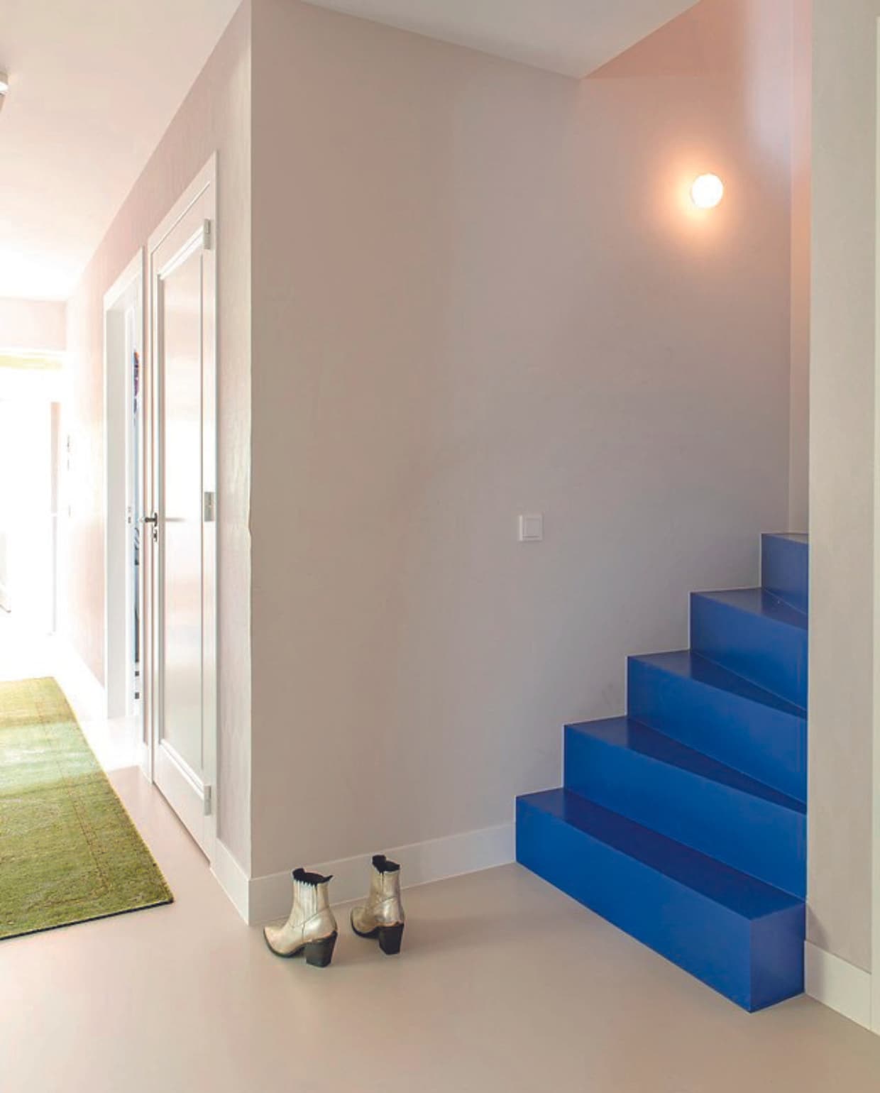 Muurverf Ral 9016, trapverf Ultra Blue van Little Greene. Vloerkleed HKliving, wandlamp Dioscuri van Artemide. vtwonen 08-2024 | styling Jeske Weel | fotografie Caroline Coehorst