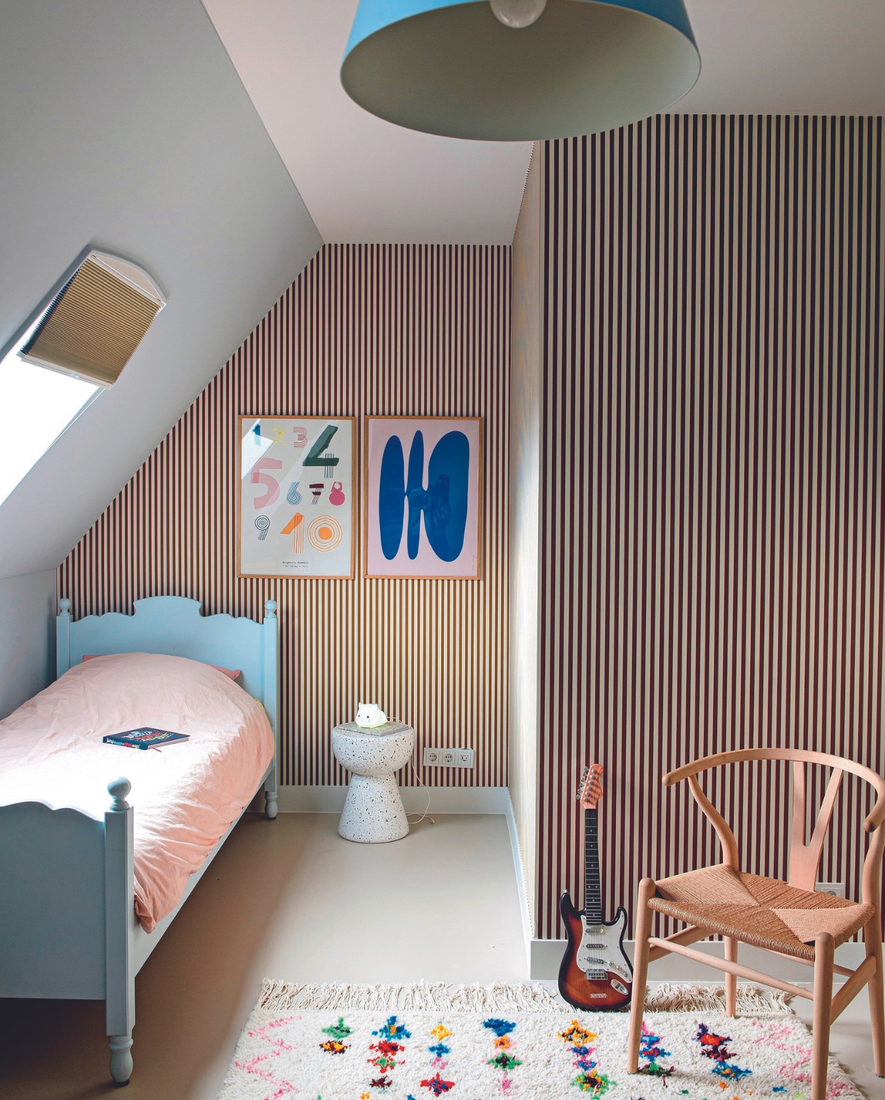 Behang Ferm Living, plisségordijnen Change Wonen. Bed antiek, dekbedovertrek Suite702, kunstwerken PSTR, bijzettafel HKliving, nachtlamp Bol, vloerkleed Etsy, stoel Carl Hansen. vtwonen 08-2024 | styling Jeske Weel | fotografie Caroline Coehorst