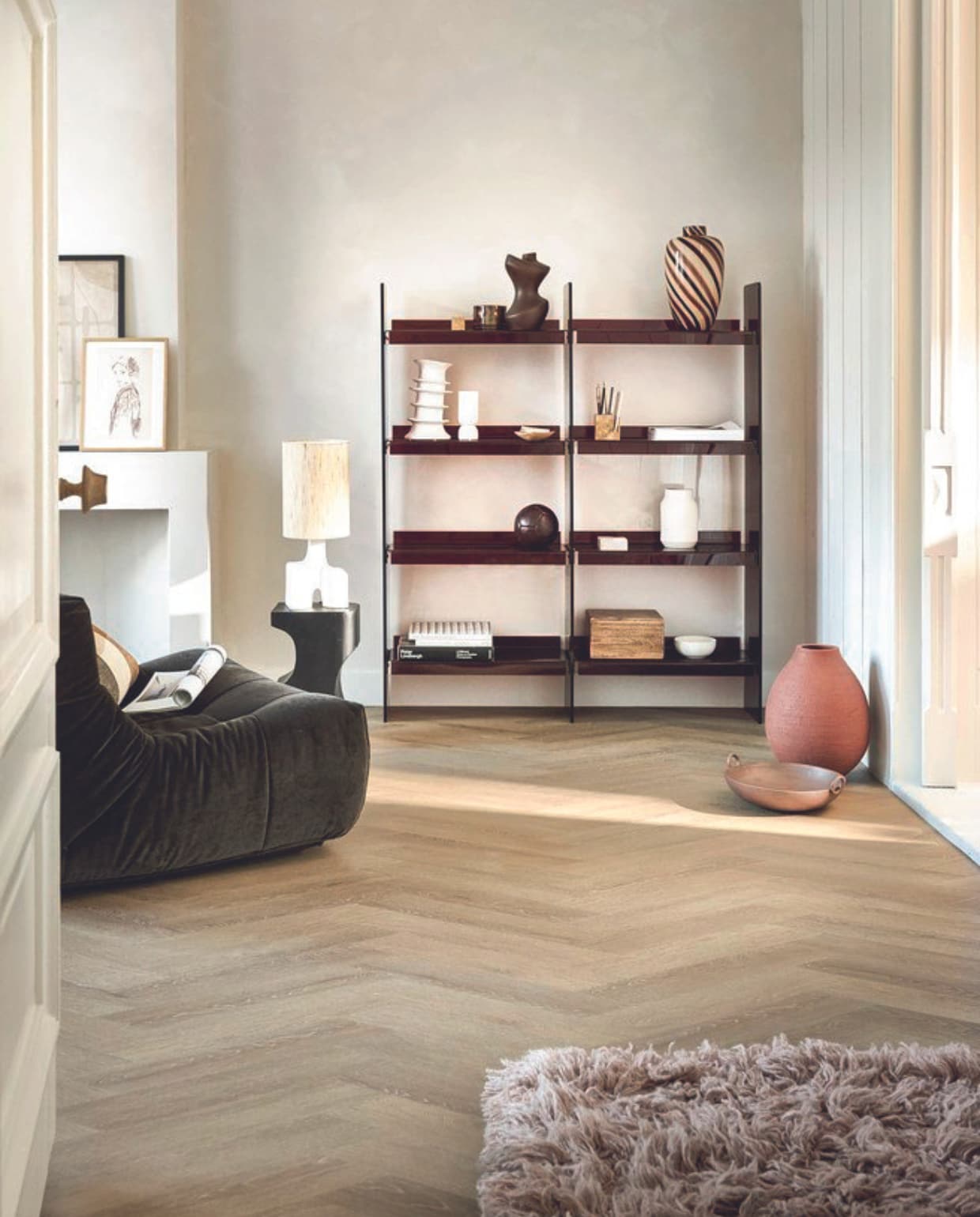 Pvc-vloer Noble in Sunkissed, gelegd in Weense punt, 53,8x11,7 cm, dryback per m² € 48,95.M.m.v. hkliving.com (wandkast, zitelement, gestreepte vaas, kussen, vloerkleed), urbannatureculture.com (bijzettafel, tafellamp, bruin object, kistje, houten doos, schaal), tinystories.nl (print), vtwonen.nl/shop (ribbelvaas van Serax, organizer van Ferm Living), zarahome.com (terracotta vaas). vtwonen 08-2024 | styling Marlies Does | fotografie Sjoerd Eickmans