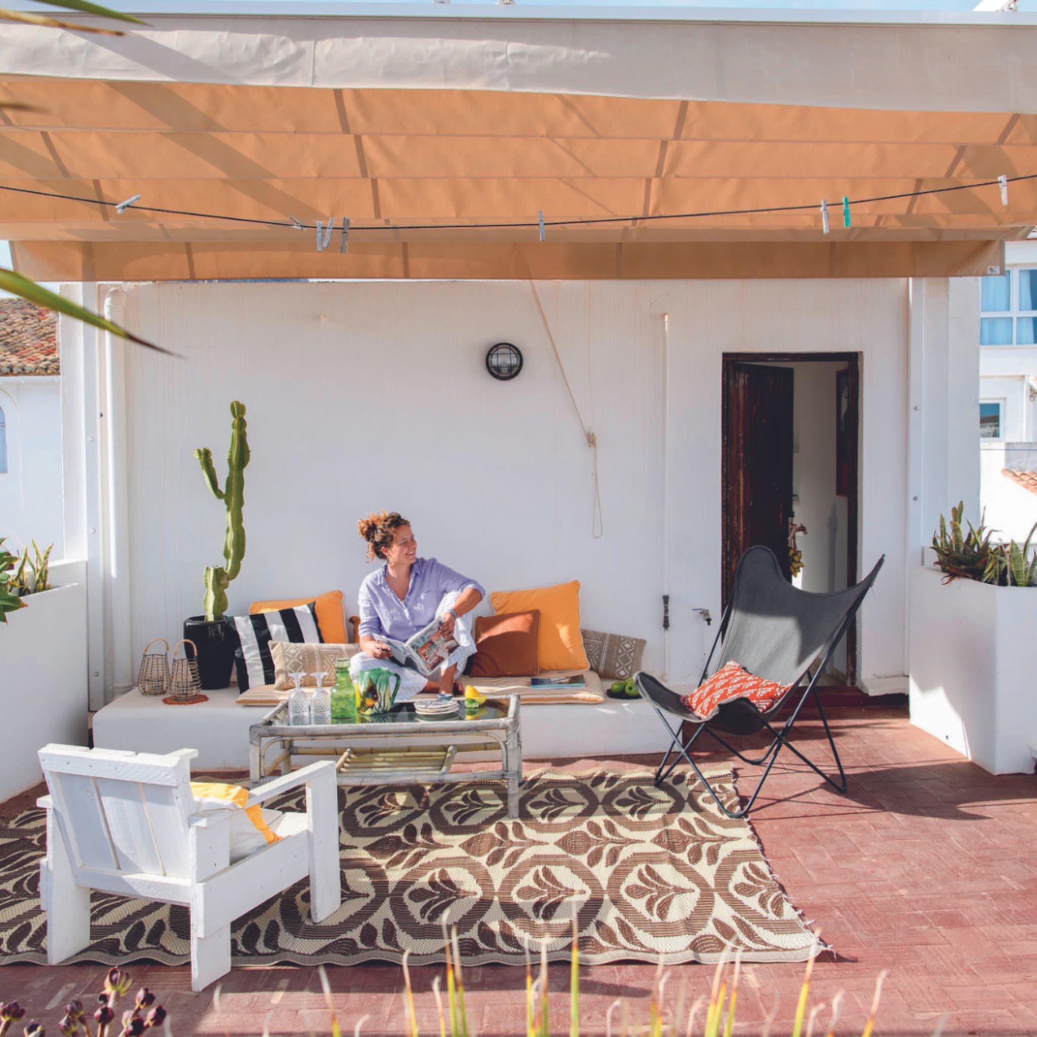 Balkon met bohemian tuinmeubels en een naturel schaduwdoek