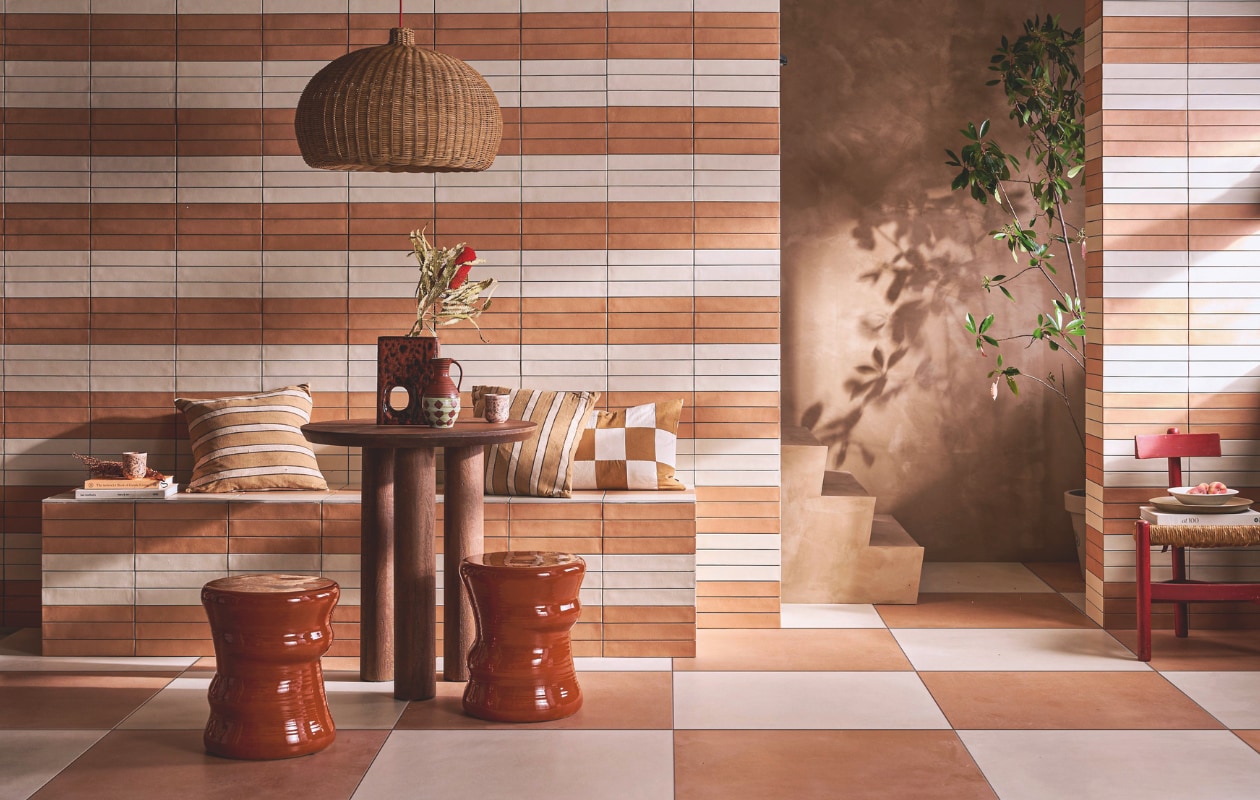 Op de vloer tegels Earth Pomice en Earth Cotto, 75x75 cm, per m² € 77,50. Op de wand en bank tegels Earth Pomice en Earth Cotto, 5x30 cm, per m² € 79,50..M.m.v. lauthentique.nl (kalkverf muur en trap in Mokka), nordal.com (eettafel Helin Cafe), vtwonen.nl/shop (krukken Pawn van Serax, lampenkap Belly en kussens van Ferm Living, vaas van HKliving, beker en diep bord van vtwonen), graublau.nl (vintage stoel). vtwonen 09-2024 | styling Cleo Scheulderman | fotografie Jeroen van der Spek