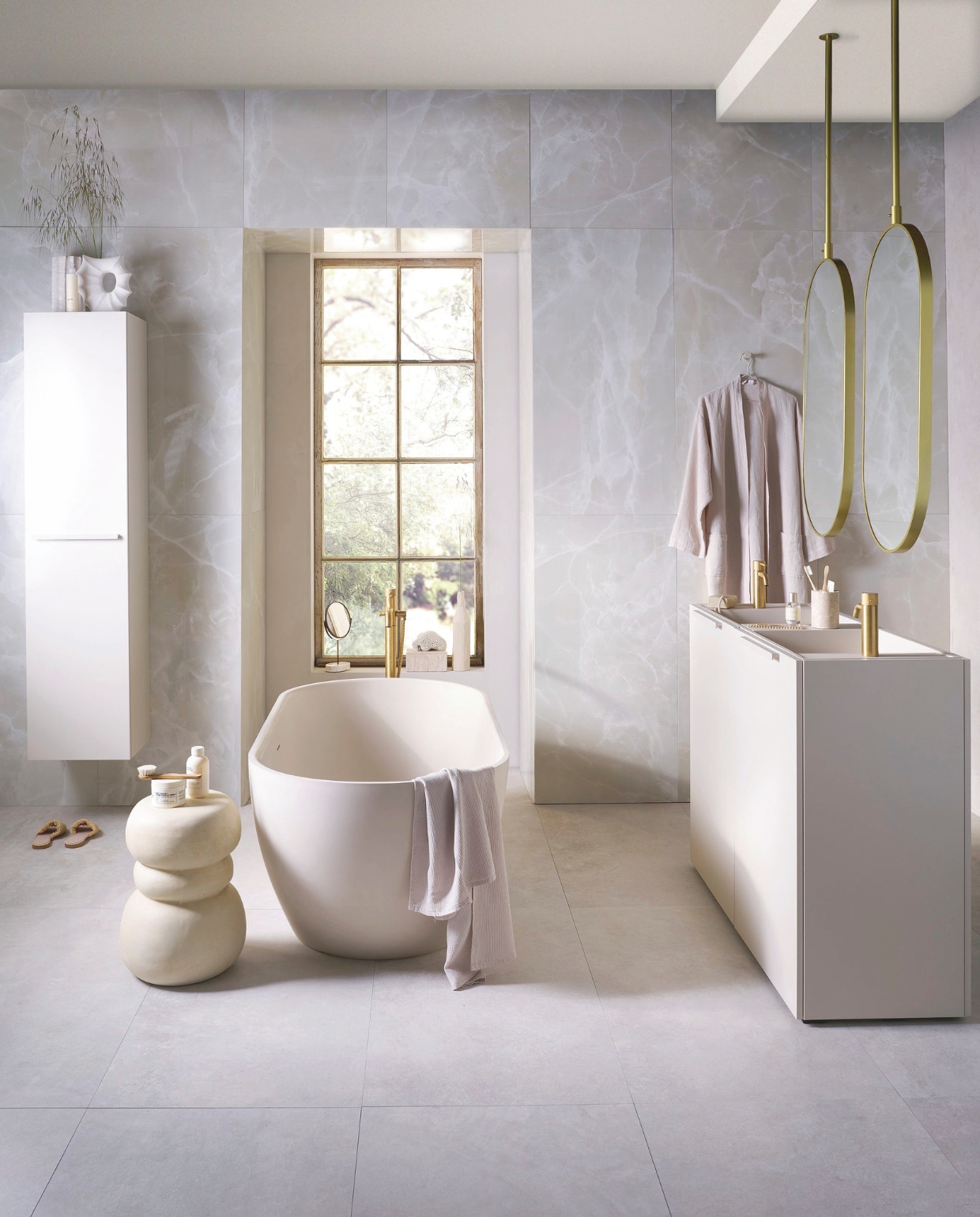 Op de vloer tegels Noble White, 60x120 cm, per m² € 69,50. Op de wand tegels Onyx Crystal White, 60x120 cm, per m² € 92,50. Top Solid bad Endless in zand, 160x73x57 cm (lxbxh), inhoud 200 liter € 4175,-. Kunststof kolomkast Bend met handgreep in matzand, 40x35,5x172 cm (bxdxh) € 1729,-. Spiegels Oval in goud, 60x90 cm (bxh) € 550,-, ook verkrijgbaar in andere afmetingen. Kunststof onderkast Wide in matzand, met twee openslaande deuren, 124,6x44,4x90 cm (bxdxh) € 1300,-, Top Solid wastafel Wide in matzand, 121x40,5x20 cm (bxdxh) € 1095,-, Top Solid plateau voor wastafel in zand, 36,8x15x8 cm (bxdxh) € 208,-. M.m.v. plieger.nl (kranen Roma, badkraan Roma), vtwonen.nl/shop (kruk van Woood), zarahome.com (badlaken, kimono, slippers, beker, zeep, borstel, spiegel op voet, travertin box), hm.com (vaas met gat), urbannatureculture.com (vaas met ribbels), lelabofragrances.com (shampoo, bodycrème, parfum). vtwonen 09-2024 | styling Cleo Scheulderman | fotografie Jeroen van der Spek