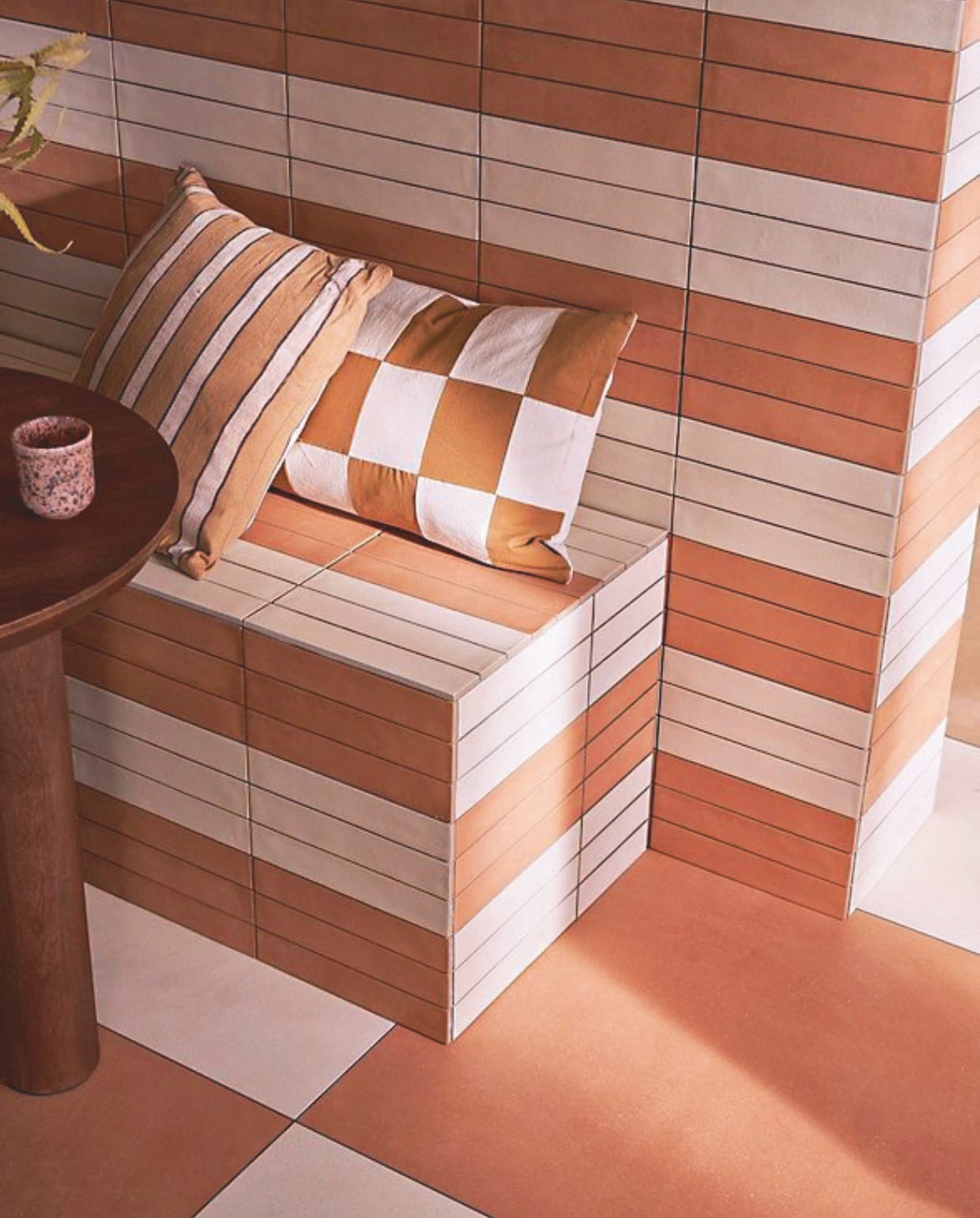 Op de vloer tegels Earth Pomice en Earth Cotto, 75x75 cm, per m² € 77,50.  Op de bank tegels Earth Pomice en Earth Cotto, 5x30 cm, per m² € 79,50.M.m.v. nordal.com (eettafel Helin Cafe), vtwonen.nl/shop (kussens van Ferm Living). vtwonen 09-2024 | styling Cleo Scheulderman | fotografie Jeroen van der Spek