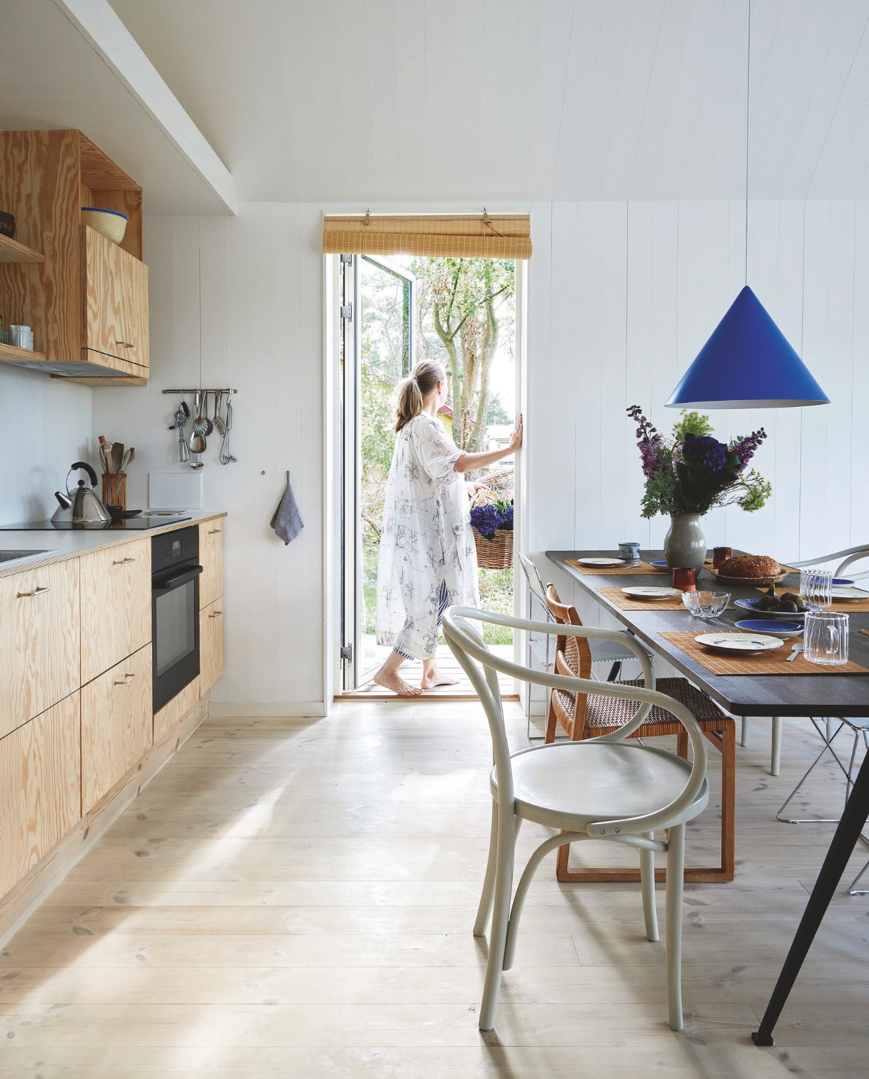 Keuken maatwerk van Pools sparrenhout met interieur van Hth, handgrepen Genbyg en apparatuur Ikea. Ketel Bird Kettle van Michael Graves voor Alessi. Eettafel Pyramid van Wim Rietveld en Friso Kramer voor Hay. Beige stoelen Thonet, zelf geschilderd. Stalen stoelen X-line van Niels Jørgen Haugesen. Hanglamp Benjamin van Benny Frandsen. vtwonen binnenkijk special 07-2024 | productie Living inside | styling Rikke Graff Juel | fotografie Anitta Behrendt