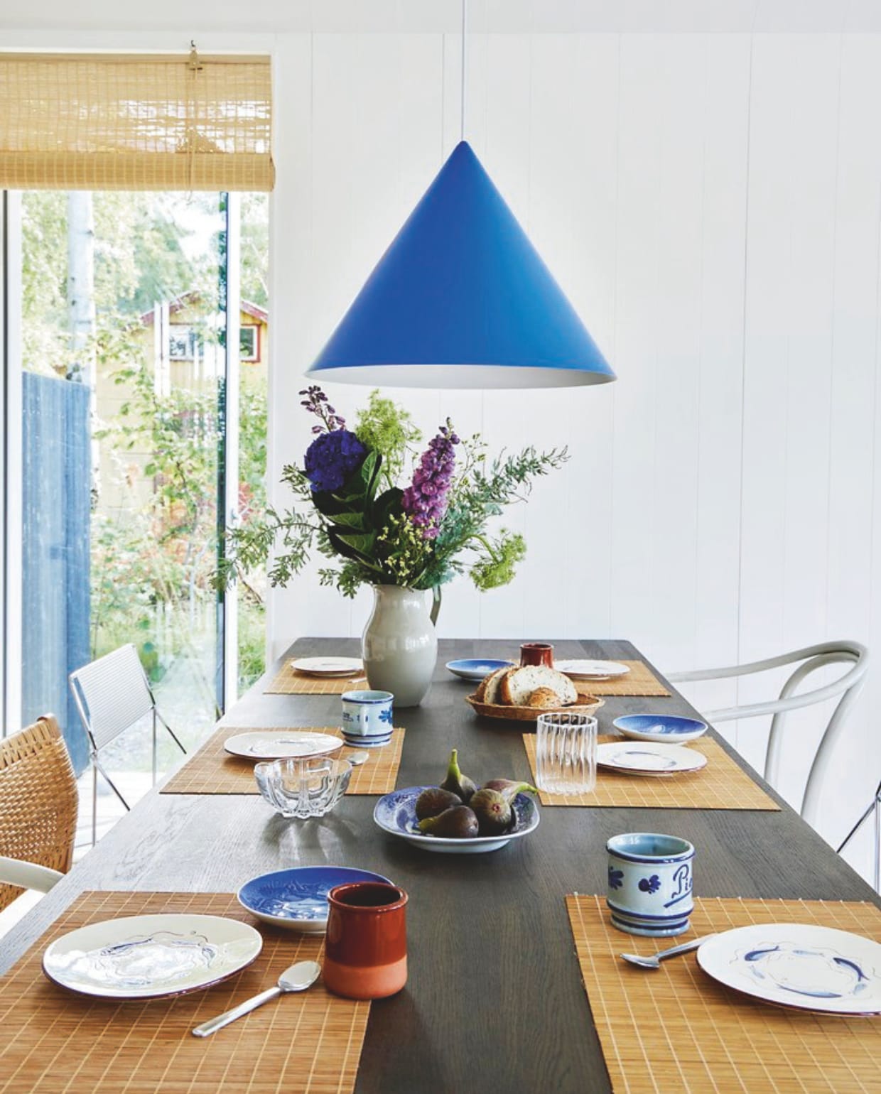 Bamboe rolgordijn Jysk, hanglamp Benjamin van Benny Frandsen, eettafel Pyramid van Wim Rietveld en Friso Kramer voor Hay. Op tafel: witte borden Knabstrup Keramik, blauwe borden Bing en Grøndal, overig kringloop. vtwonen binnenkijk special 08-2024 | productie Living inside | styling Rikke Graff Juel | fotografie Anitta Behrendt