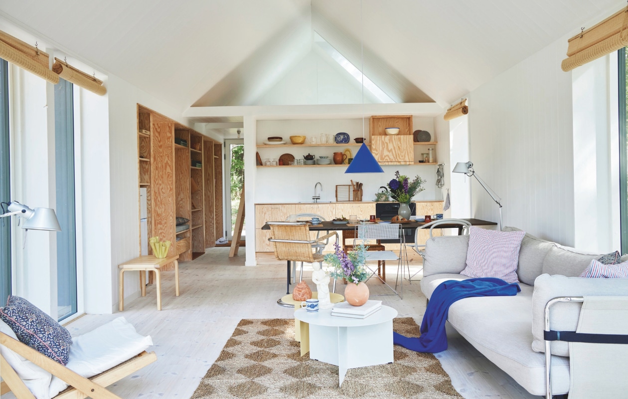 Vloerkleed vintage, bank en salontafels Slit van Hay, kussens Studio Feder, deken Helene Blanche voor Paustian, bamboe rolgordijnen Jysk, vloerlampen Tolomeo Artemide. Fauteuil rechts Hans Wegner, opnieuw bekleed, eettafel Pyramid van Wim Rietveld en Friso Kramer voor Hay, beige stoelen Thonet, zelf geschilderd, stalen stoelen X-line van Niels Jørgen Haugesen, hanglamp Benjamin van Benny Frandsen. vtwonen binnenkijk special 08-2024 | productie Living inside | styling Rikke Graff Juel | fotografie Anitta Behrendt