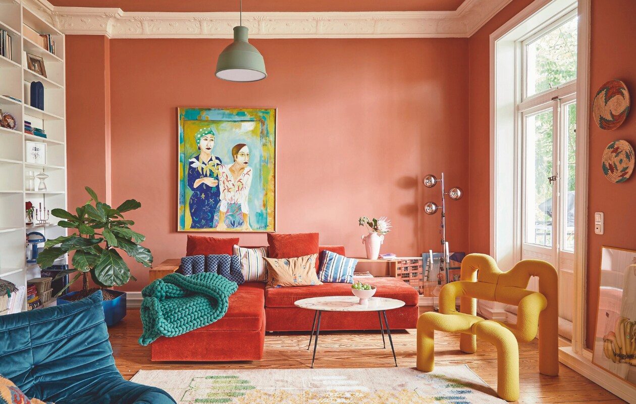 Blauwe fauteuil Togo van Ligne Roset, gele fauteuil Varier Ekstrem van Terje Ekstrøm, lamp Muuto, bank Brühl, Gabbeh-vloerkleed van Rugtales. Kunstwerk vintage, kunstenaar onbekend. Muurkleur Red Earth van Farrow &amp; Ball. vtwonen 09-2024 | fotografie Nassim Ohadi