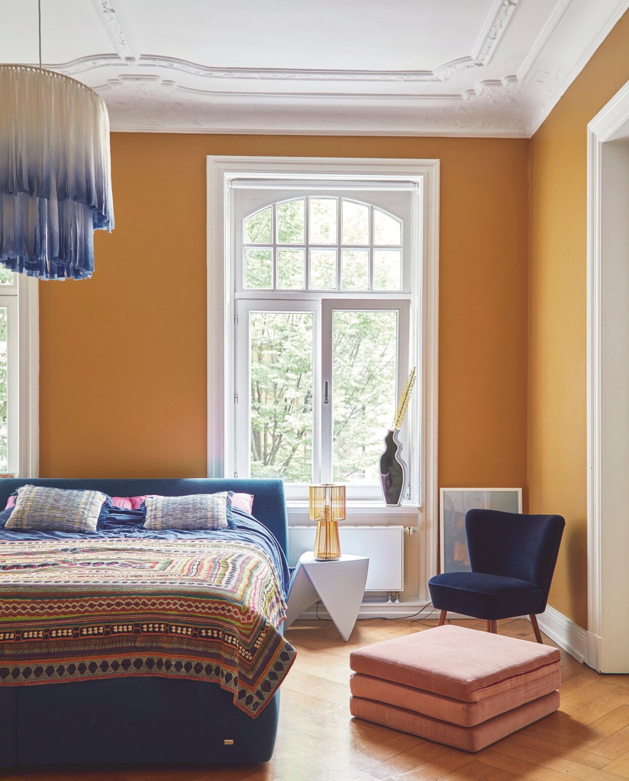 Bed Ruf Betten, handgemaakte deken uit Pakistan, nachtkastje vintage. Tafellamp en vintage plafondlamp van Ikea. Poef en stoel bekleed met oude fluwelen gordijnen. Print Drool, muurkleur India Yellow van Farrow &amp; Ball. vtwonen 09-2024 | fotografie Nassim Ohadi