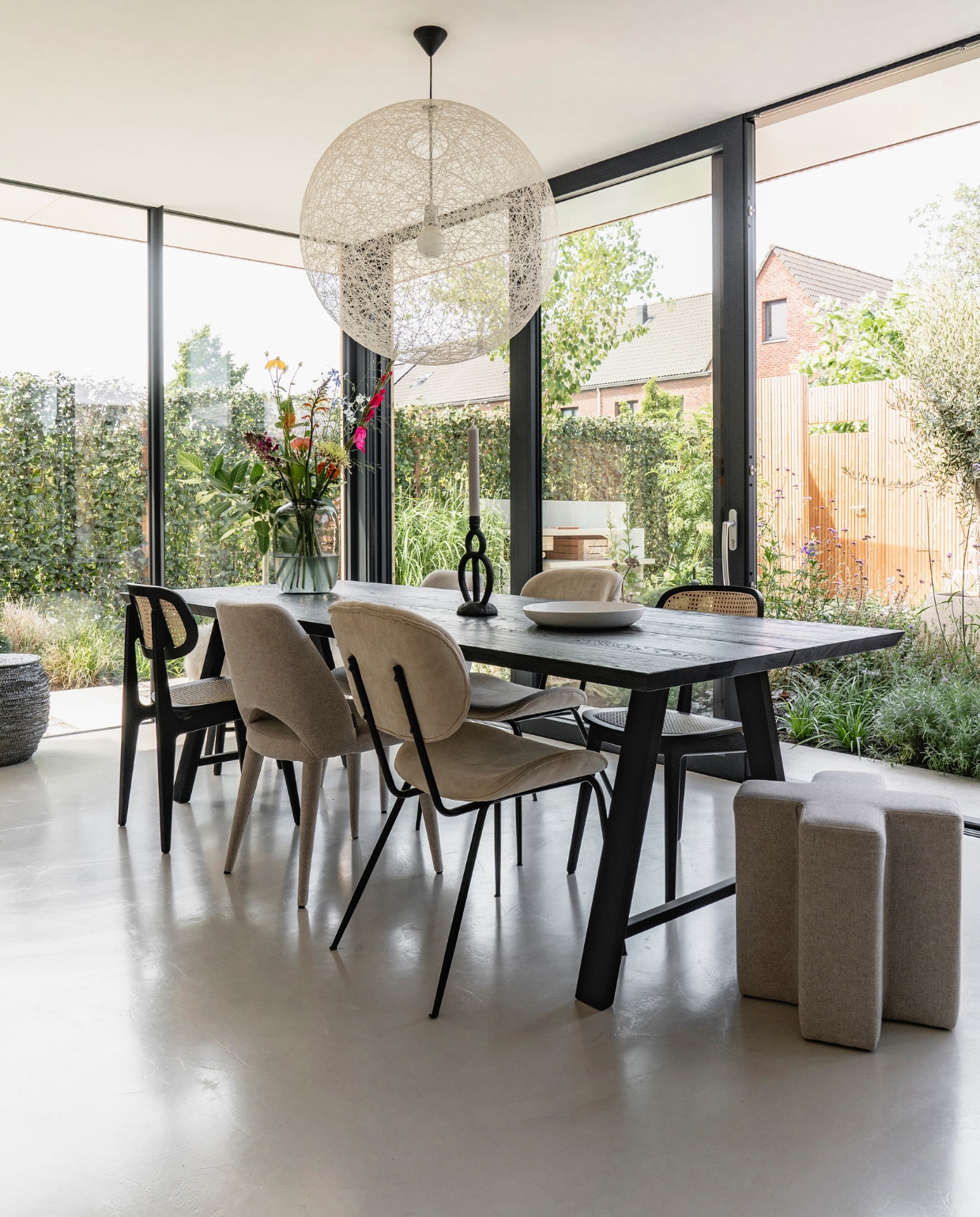 Vloer microcement via TAV Microcement. Ramen via aannemer. Eettafel Vincent Sheppard. Stoelen vooraan v.l.n.r. Vincent Sheppard, Pols Potten, HKliving. X-vormig krukje Pols Potten. Kandelaar Bloomingville. Hanglamp Moooi. Bord op tafel vintage. Overig herkomst onbekend. vtwonen 08-2021 | fotografie Muk van Lil