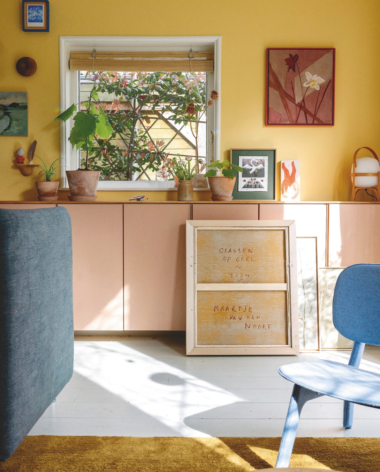 Kast zelfgemaakt/Ikea, muurverf Leeuw van Fairf. Stoel Ligne Roset, vloerkleed Ikea, lamp Cesta van Miguel Milá, schilderijen Maartje, knipwerk Broeder Dieleman, schilderij op hout Gemma Oosterhof. Bloempotten Julie van Ninetta Mariani via May & June.