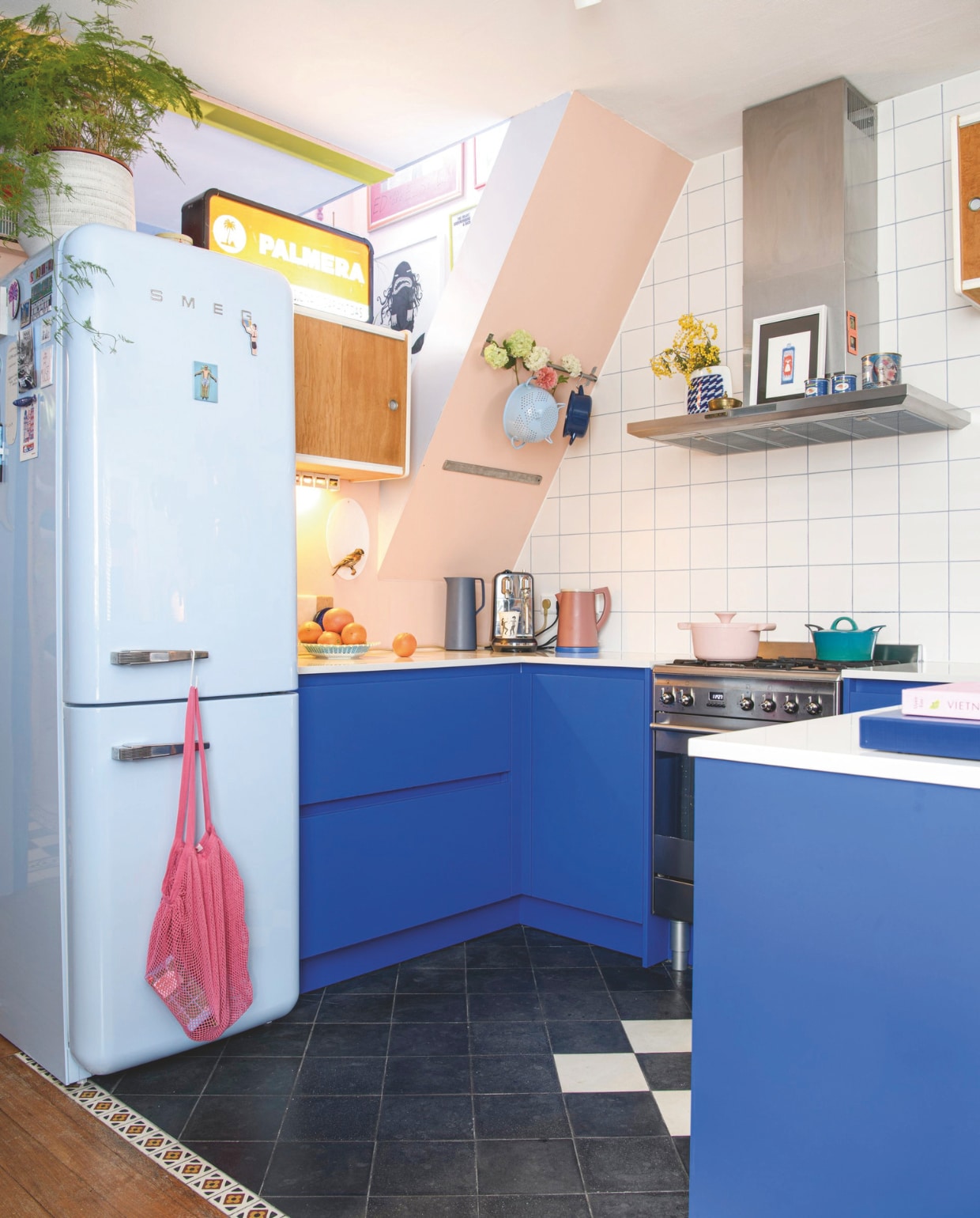 Koelkast Smeg, tafelpoten van Tiptoe via Hoeked, tafelblad zelfgemaakt, hanglamp Vintage Asylum, tegels Wout’s Tegelhandel, wandkasten Marktplaats, oranje lichtbak uit tweedehandswinkel in Porto. Houten vloer lag al in het huis. Muurverf Perzik en Retro Blauw van Decoverf. Verf deurkozijn Middenblauw van Decoverf. vtwonen 09-2024 | styling Inge van Lieshout | fotografie Louis Lemaire
