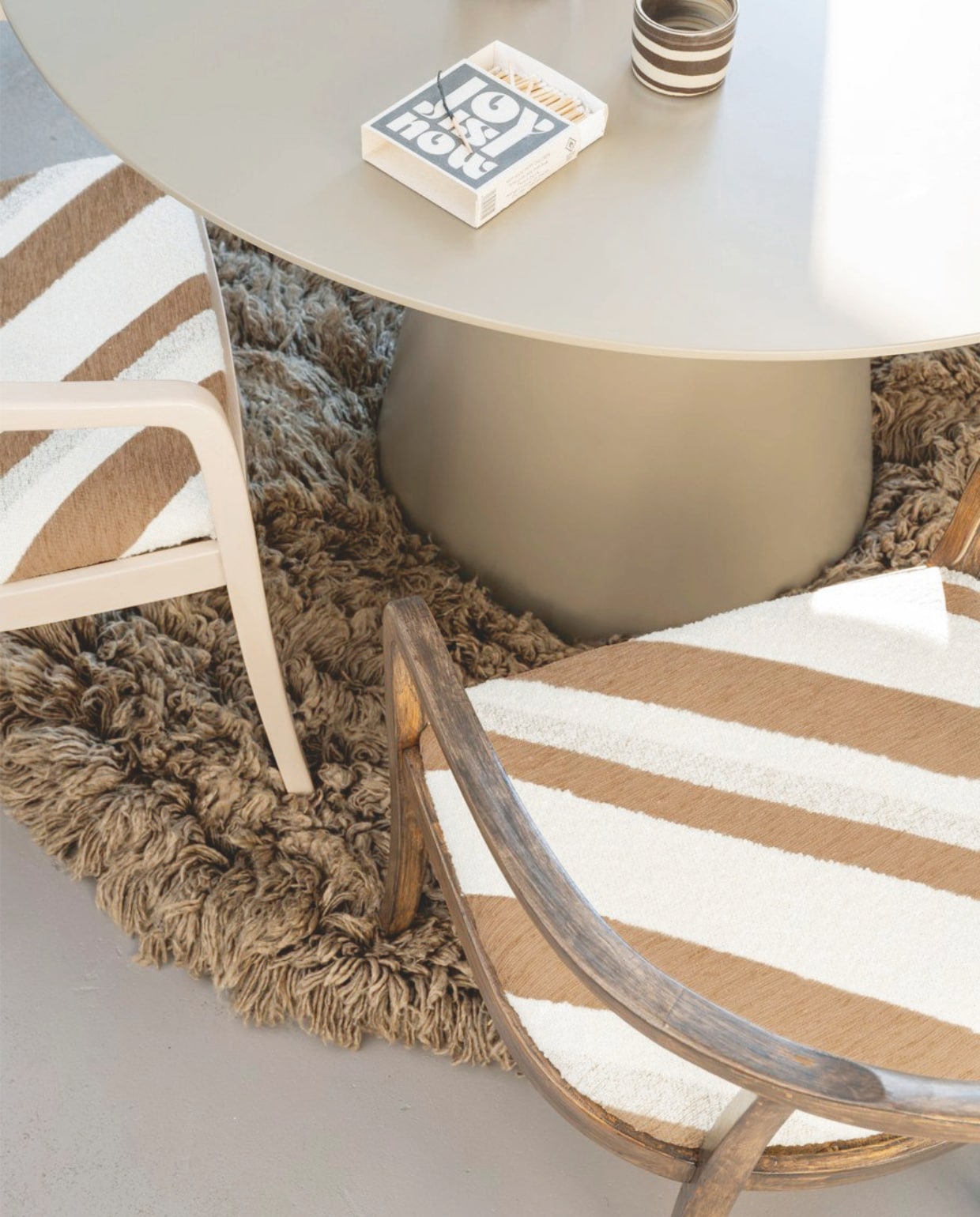 Stof Slalom, jacquard geweven chenille en bouclé, 140 cm breed, per meter € 111,60  (casamance.com). Wollen vloerkleed Fluffy van HKliving, 150 cm (Ø) € 675,-, mdf tafel Jorre van Woood, 120x76 cm (Øxh) € 499,- (vtwonen.nl/shop). Bruin-witte koffiekop € 24,- (studio-potterdam.com). vtwonen 09-2024 | styling Kelly van Gendt | fotografie Stan Koolen | m.m.v. de Kringloper Naarden