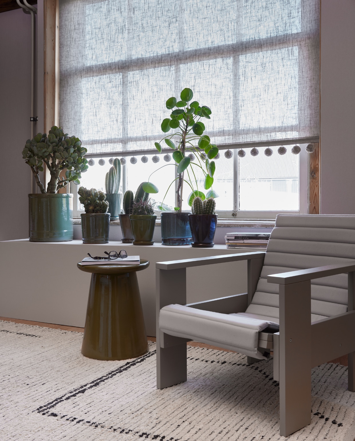 Rolgordijn Beach van vtwonen, 90x190 cm (bxh) vanaf € 78,99, verf op vensterbank Flax van vtwonen, per liter € 15,05 (karwei.nl). Pompomband Big Pom Braid Silt, per meter € 52,50 (villanova.co.uk). Vloerkleed van HKliving, gerecycled katoen, 200x300 cm  € 479,-, keramieken bijzettafel Button van vtwonen, 35x45 cm (Øxh) € 129,- (vtwonen.nl/shop). Houten loungestoel Crate, 58x77x64,5 cm (bxdxh) € 295,-, loungekussen Crate € 95,- (hay.nl). Planten met potten (plantje.nl). vtwonen 05-2023 | styling Marianne Luning | fotografie Alexander van Berge