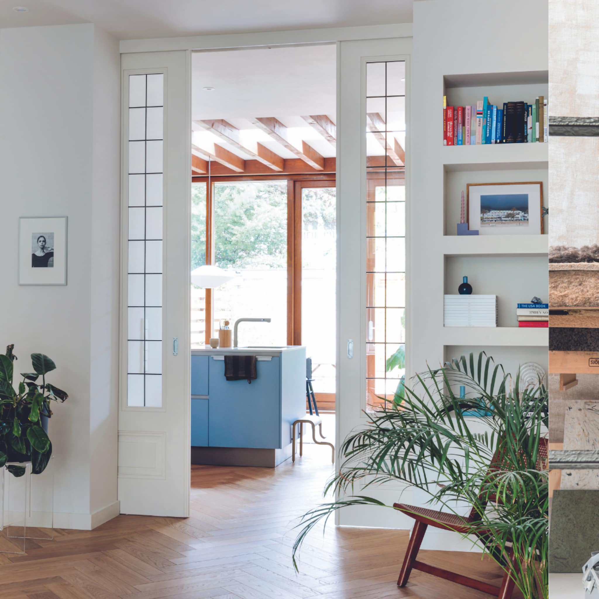 Houten vloer met een blauwe keuken en lichte wanden