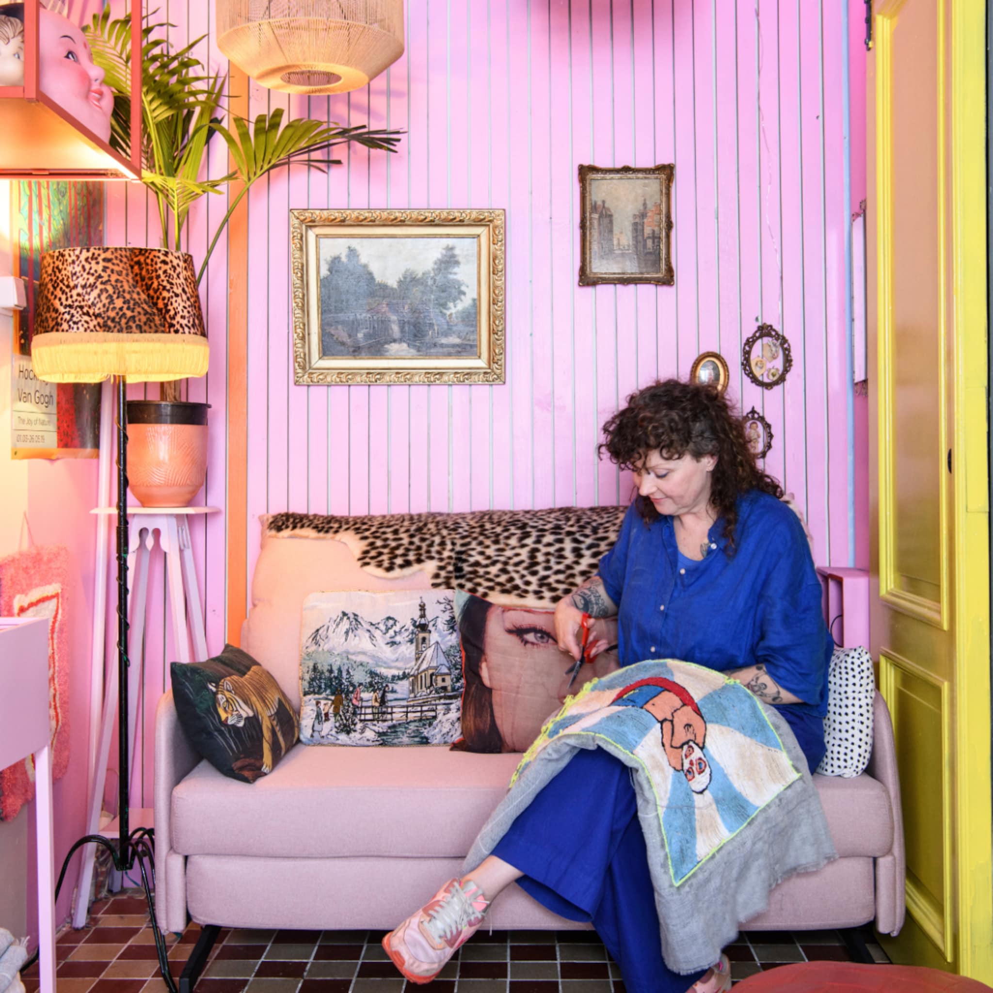 Eclectische woonkamer met een roze wand en bank, dierenprints en accessoires in goud