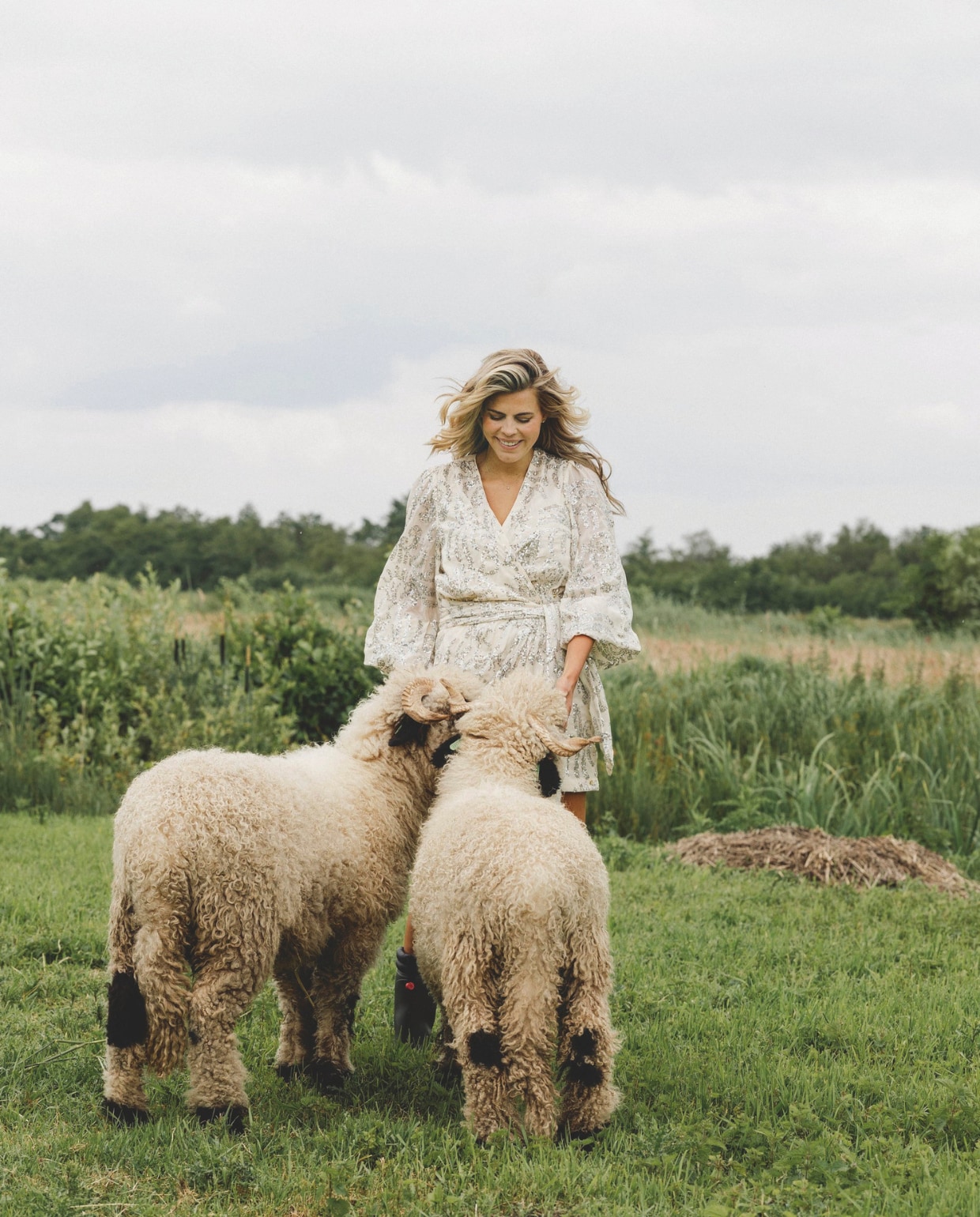 Elke ochtend, als de kinderen naar school zijn, gaat Kim de makke schapen Ollie en Bollie eten geven. Kim draagt hier een jurkje en laarzen van Poespas. stijlvol wonen 9-2024 | Fotografie Stefanie De Neve