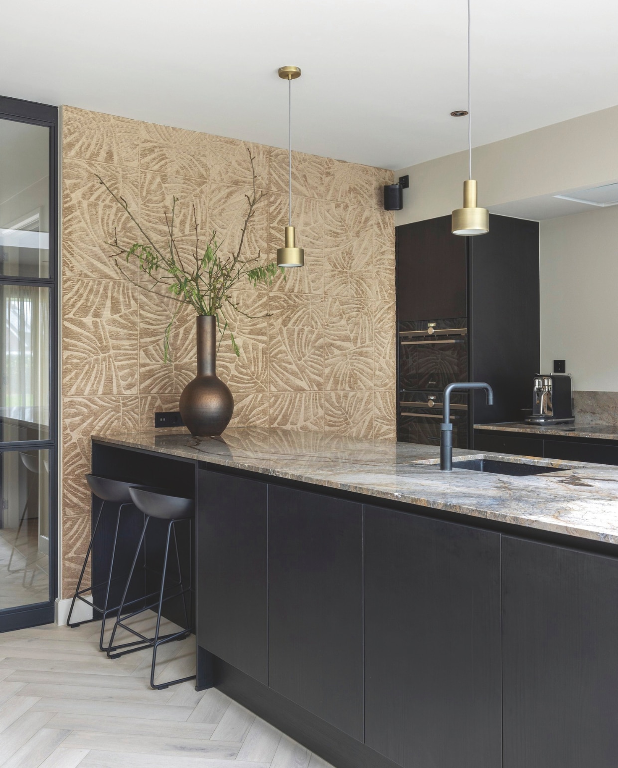 De keuken was al in het huis aanwezig. Eetkamerbank Jacky van Keijser&amp;Co en het bijzettafeltje van Duran Interiors zijn aangeschaft via Violier at Home. De kussens zijn van het eigen label van Violier at Home. Ook alle accessoires komen daarvandaan. Corina en Rob hebben het witte werkblad vervangen door een natuurstenen blad van Norvold, gerealiseerd door Kwieziens. Het geluidsabsorberende behang van Arte is geleverd door Violier at Home. Het kunstwerk is van Taftique. stijlvol wonen 10-2024 | foto Anne Gambon