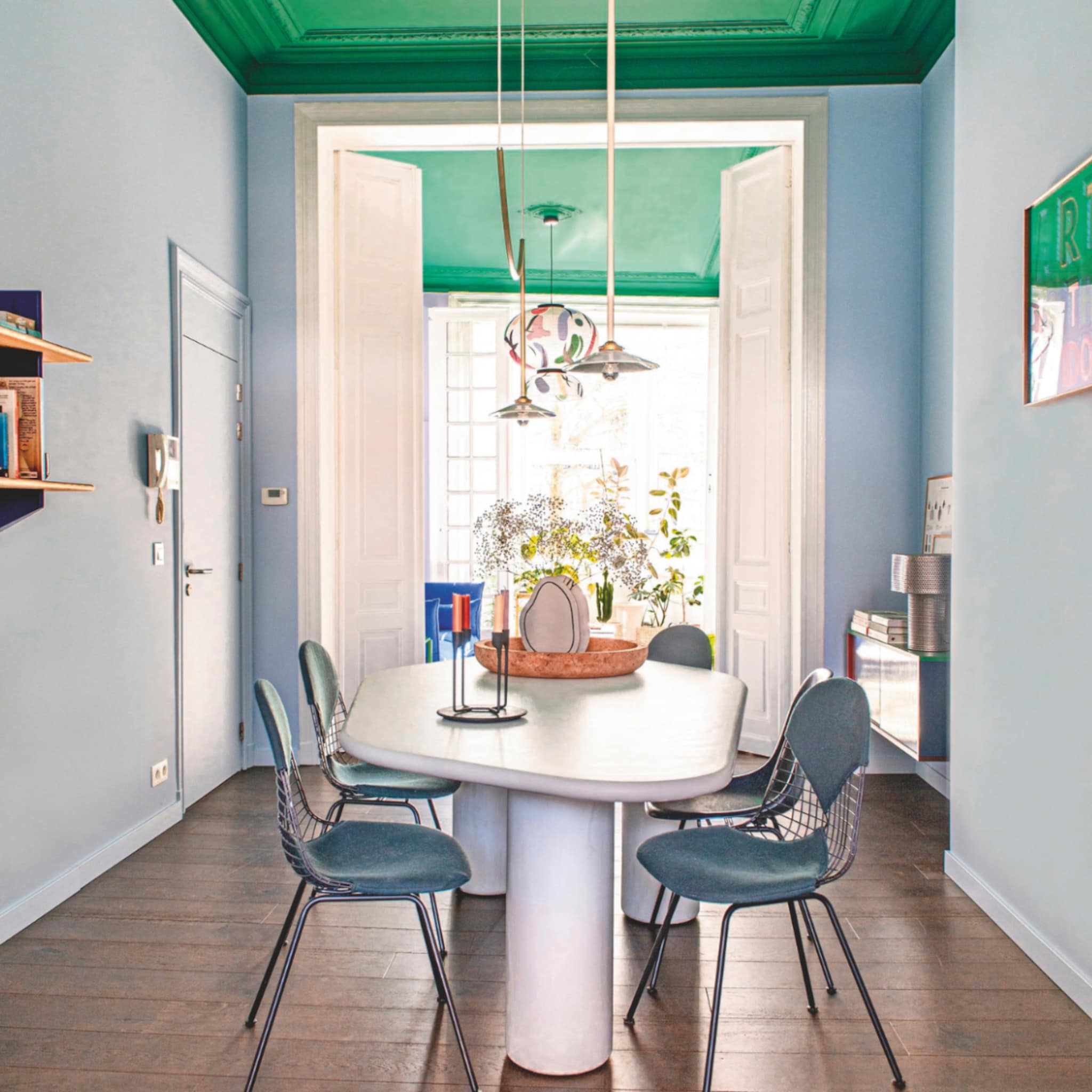 Kleurrijke eetkamer met blauwe stoelen en een groen plafond