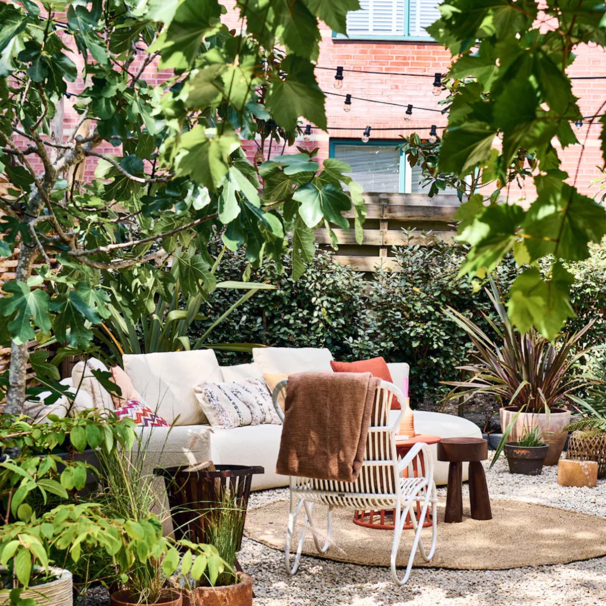 Mediterrane tuin met een moderne loungebank en kleurrijke buitenkussens