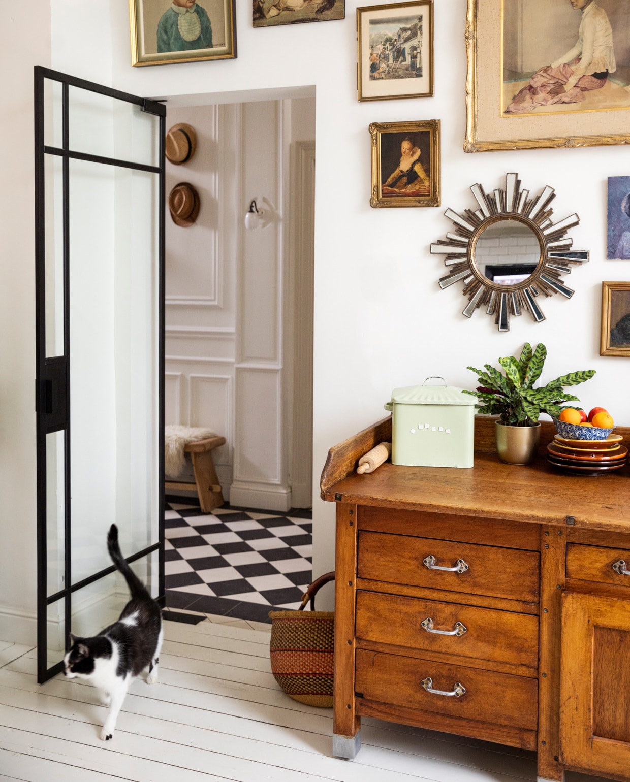 Verf muur en vloer Ral 9010, vloertegels hal Villeroy &amp; Boch. Bank Polspotten, schapenvacht Ikea, wandlamp ’t Glashuys. Lijsten kringloopwinkels en rommelmarkten, spiegel brocante, keukenblok/oud bakkersmeubel Woontheater. Mand markt, blik souvenir, plant en pot Van Uytsel, servies Marokkaanse winkel. Overig onbekend. vtwonen 10-2023 | styling Ilona Jongepier | fotografie Dana van Leeuwen